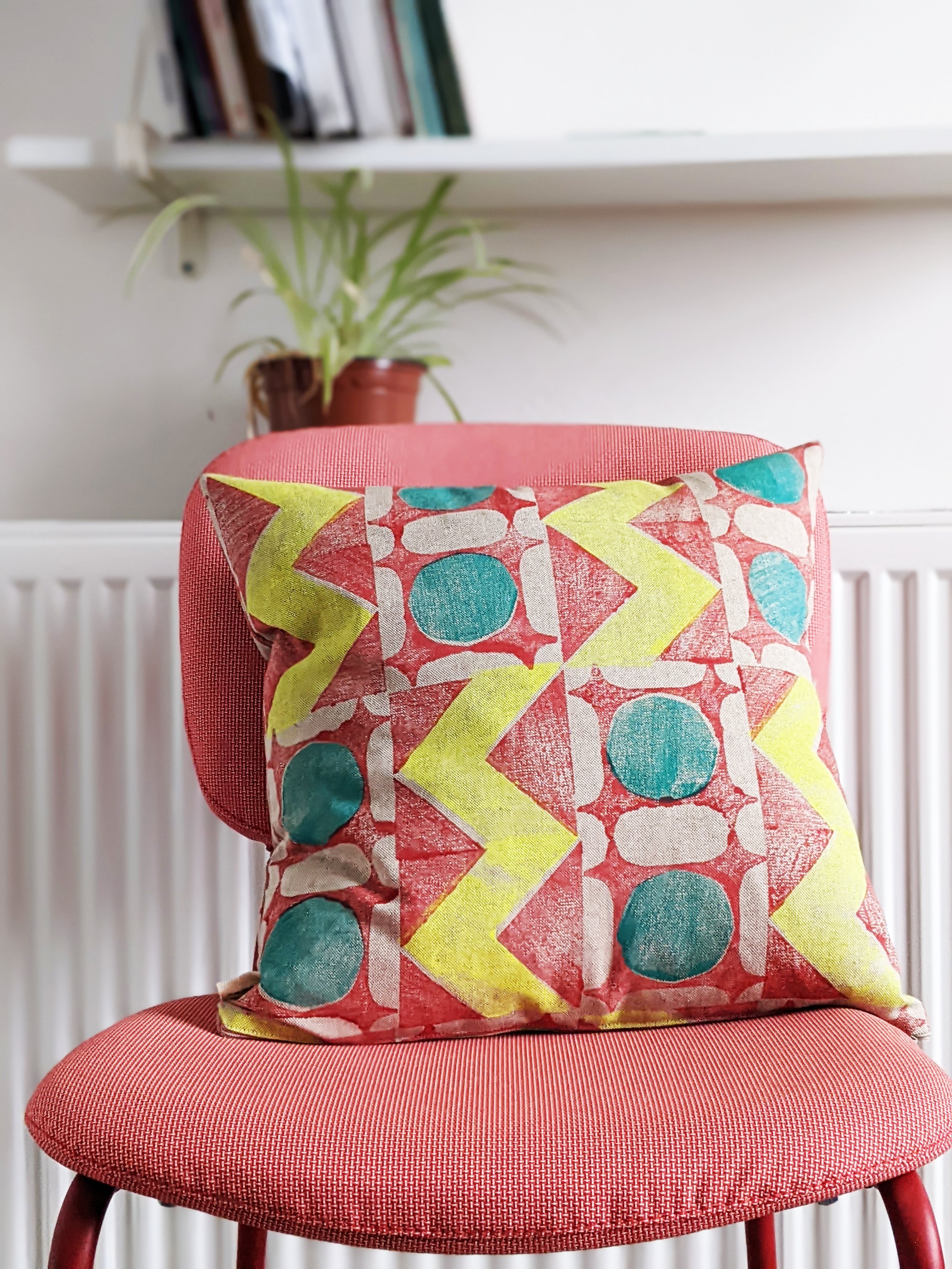 bright interior scene with cushion on red chair in bold geometric print in scandinavian style