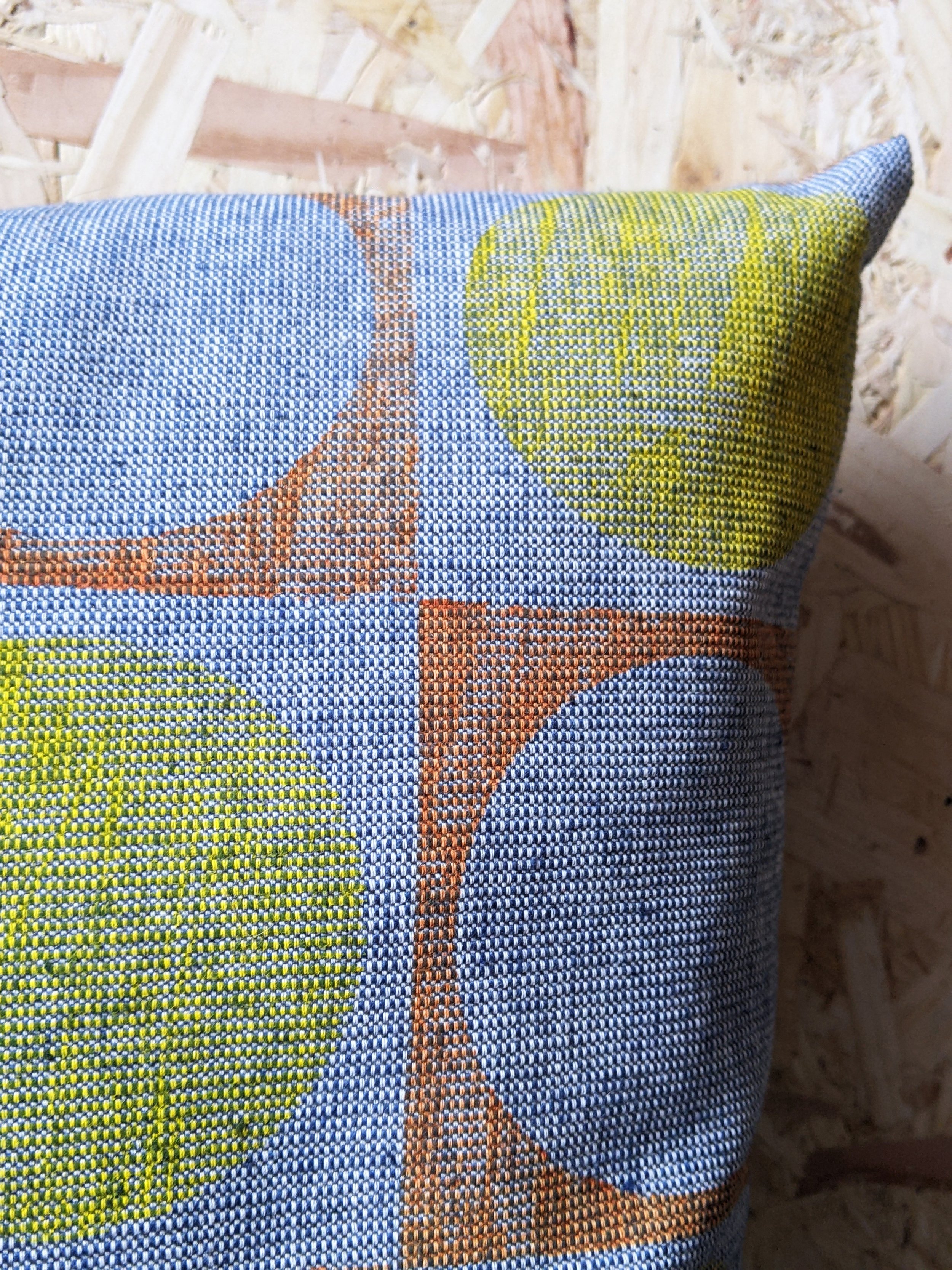 close-up detail of ribbed texture of blue fabric with and circular yellow print and architecture inspired pattern
