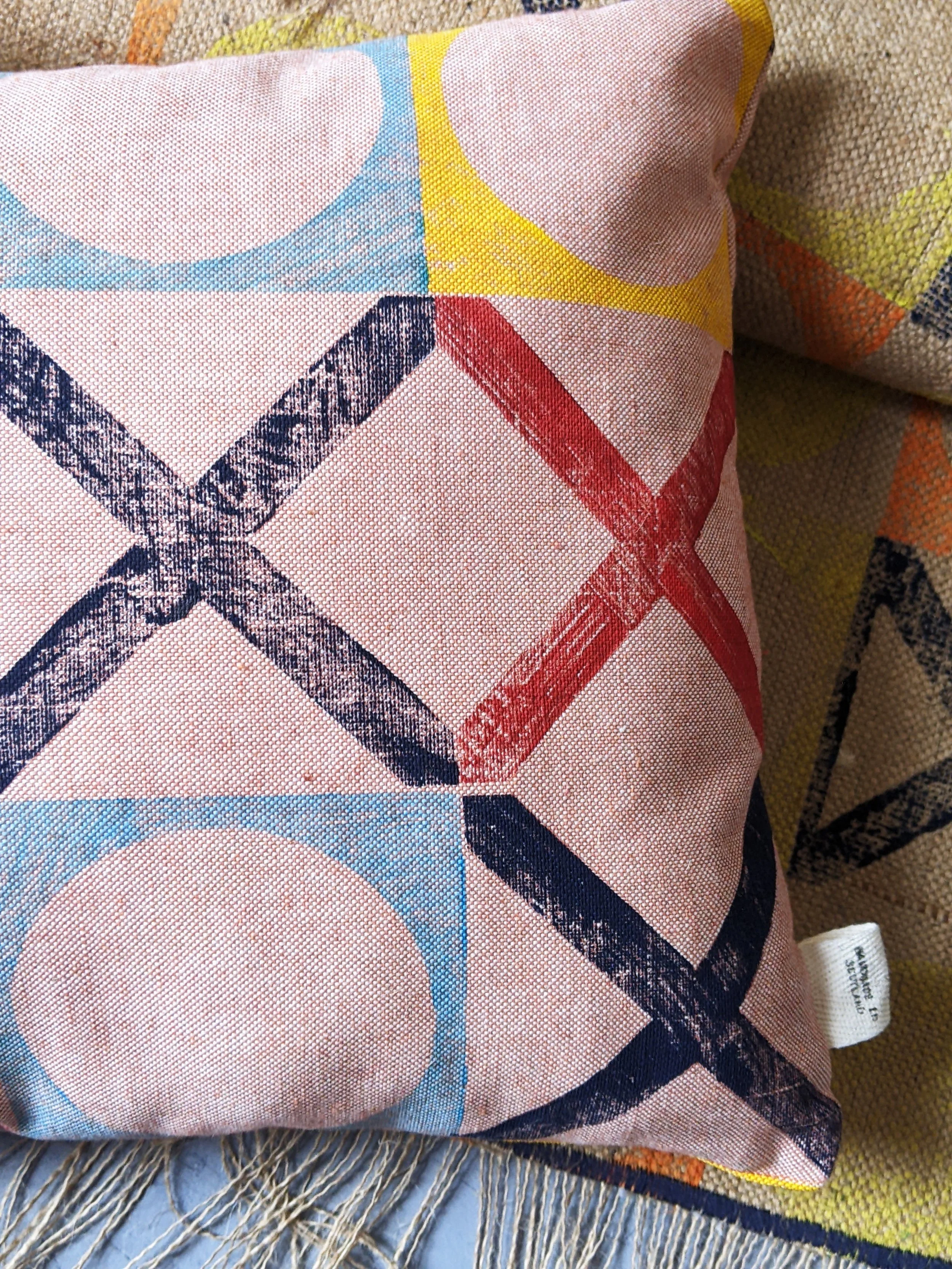 close-up detail of hand block printed colourful pattern on orange cushion with nautical-inspired print