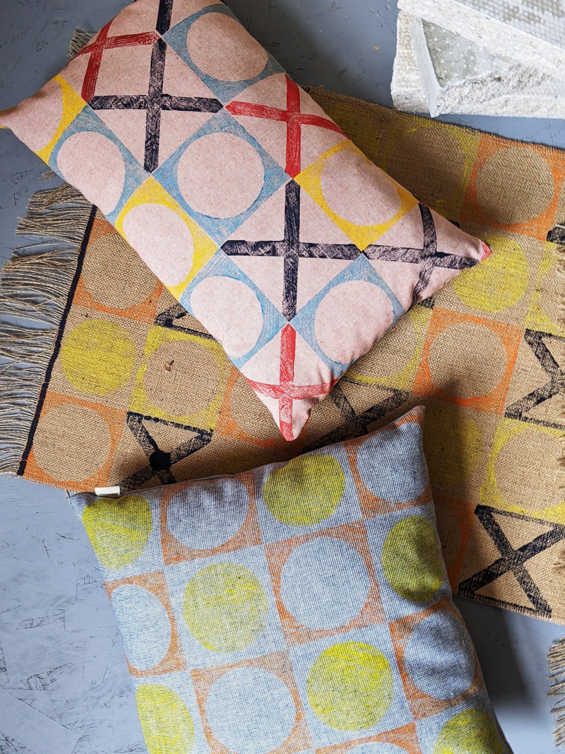 cushions on grey studio floor in geometric, nautical inspired abstract patterns with industrial decor