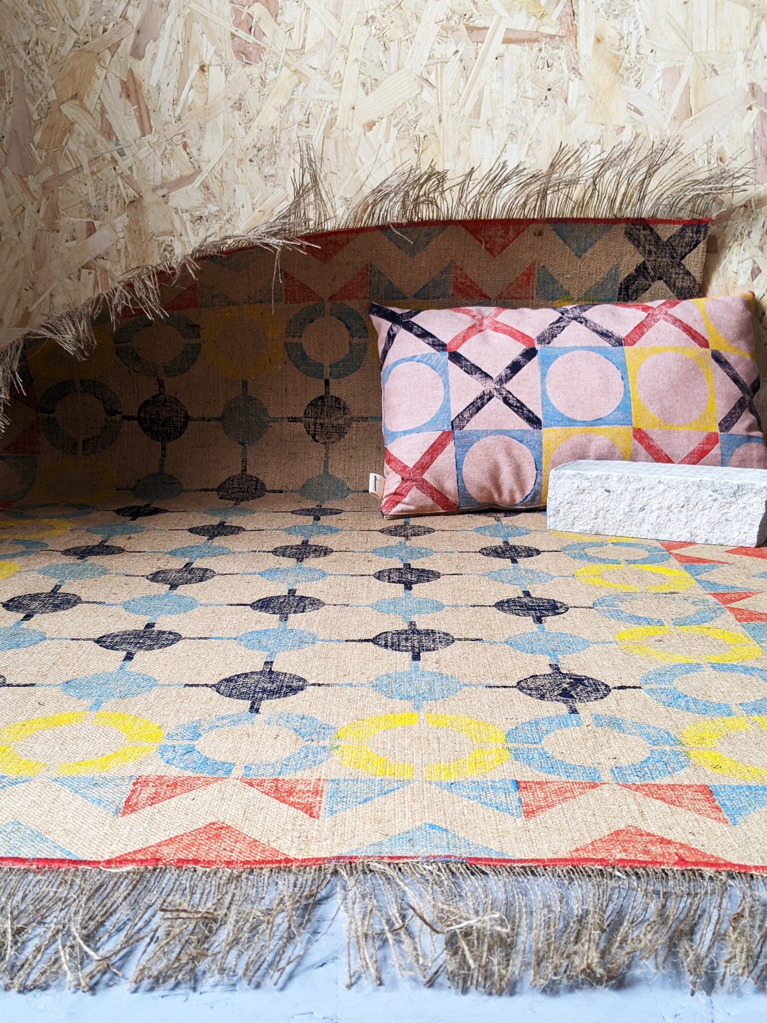 studio scene with nautical inspired industrial rug with abstract geometric bold fun pattern and cushion