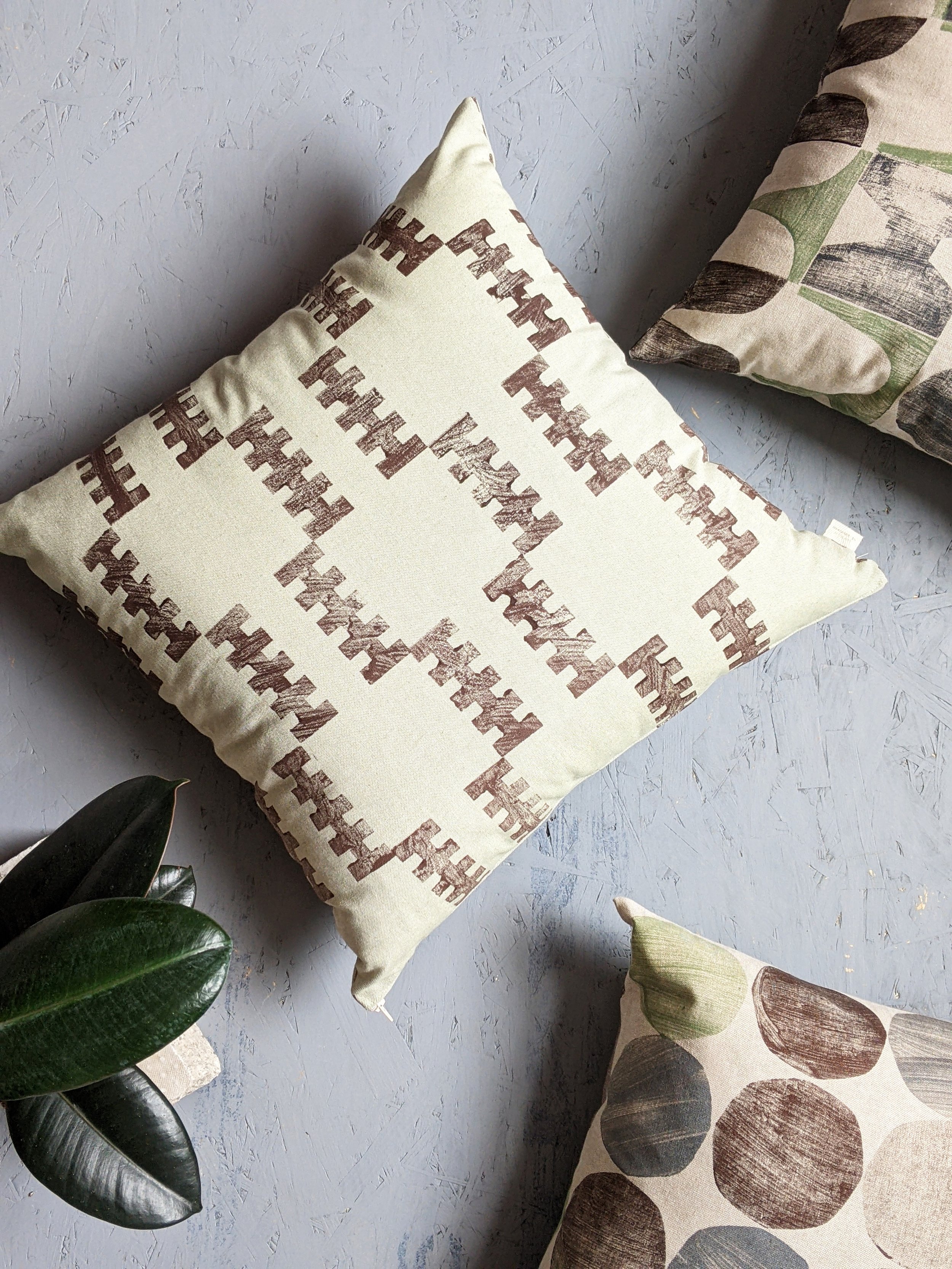 cushions on studio floor in monochrome decor, green and brown tones in block printed brutalism inspired prints