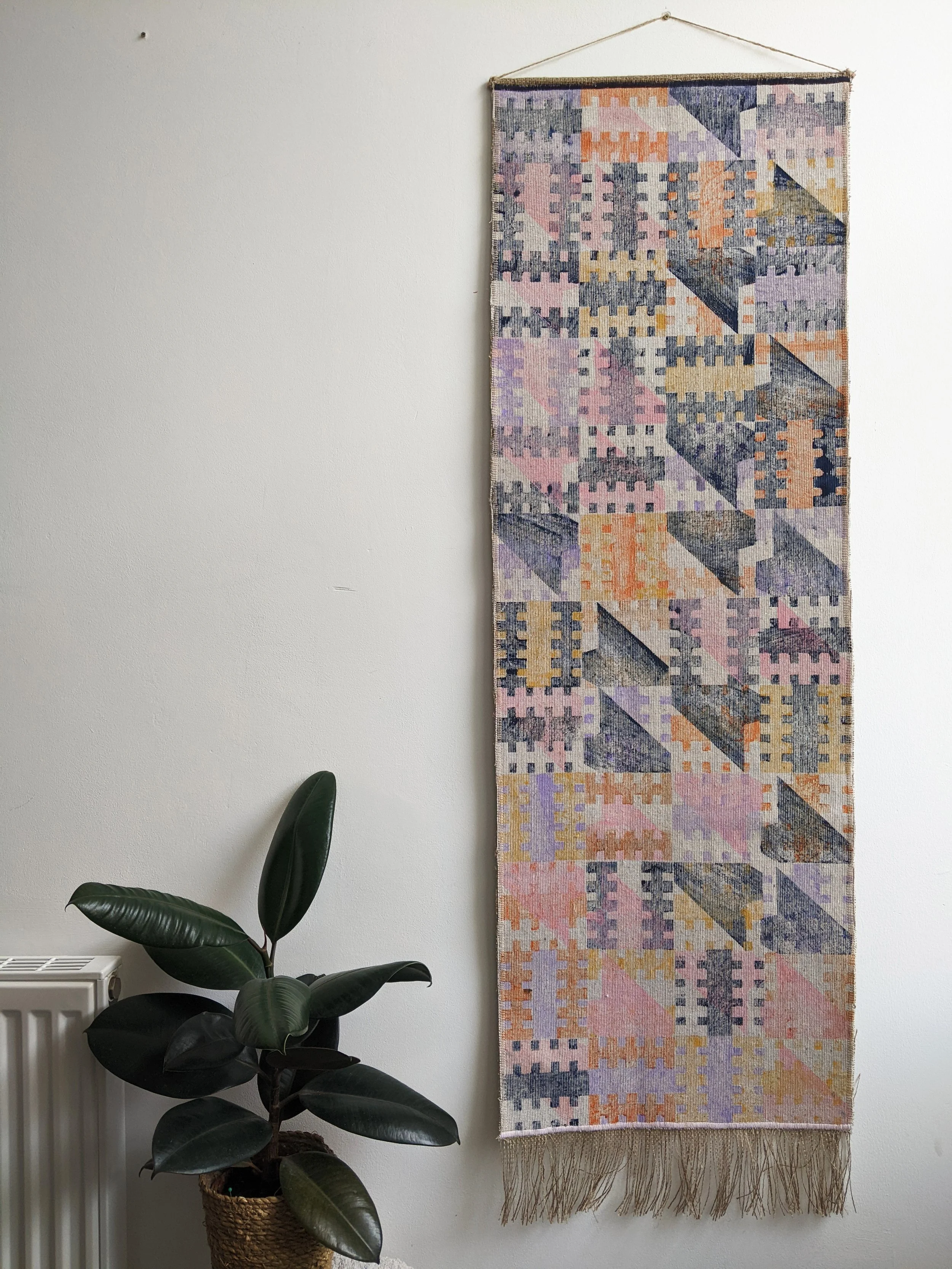 white wall with colourful architecture-inspired wall hanging in pastel colours