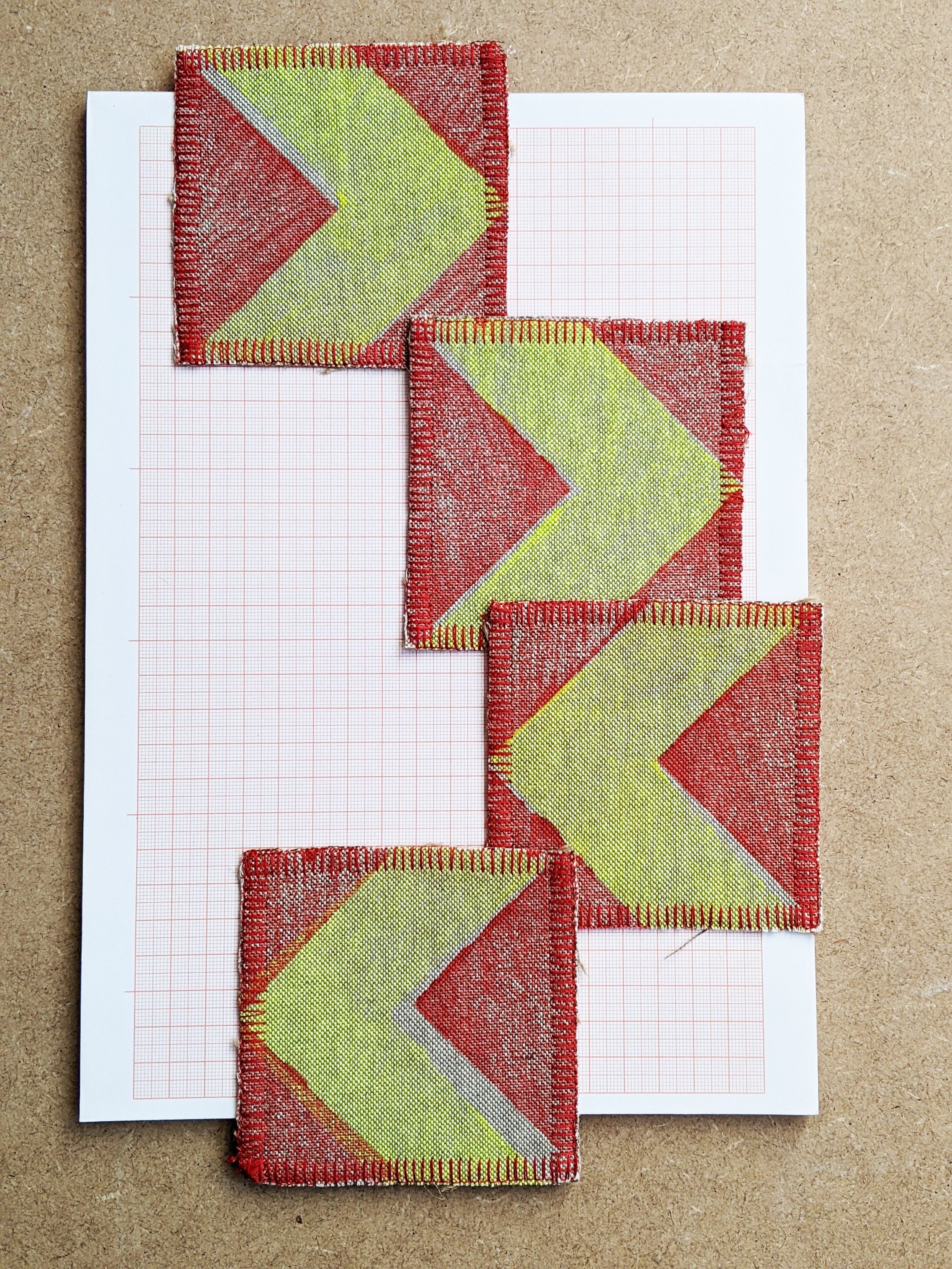 four coasters with fluorescent yellow chevron print and red background laid on graph paper