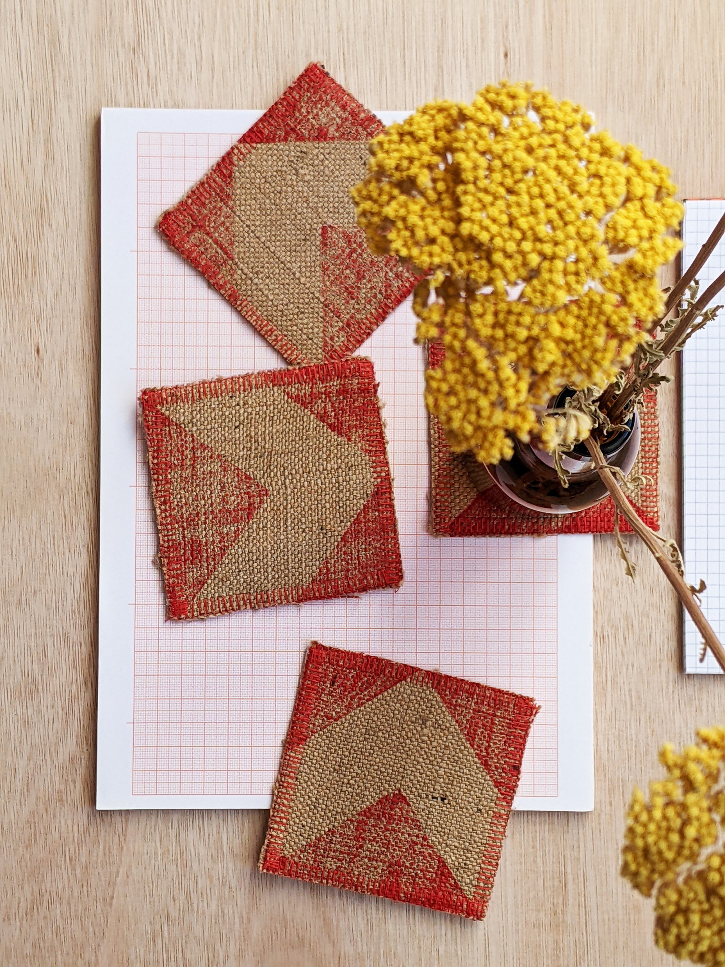 studio desk with red chevron print on jute coasters, graph paper and flowers
