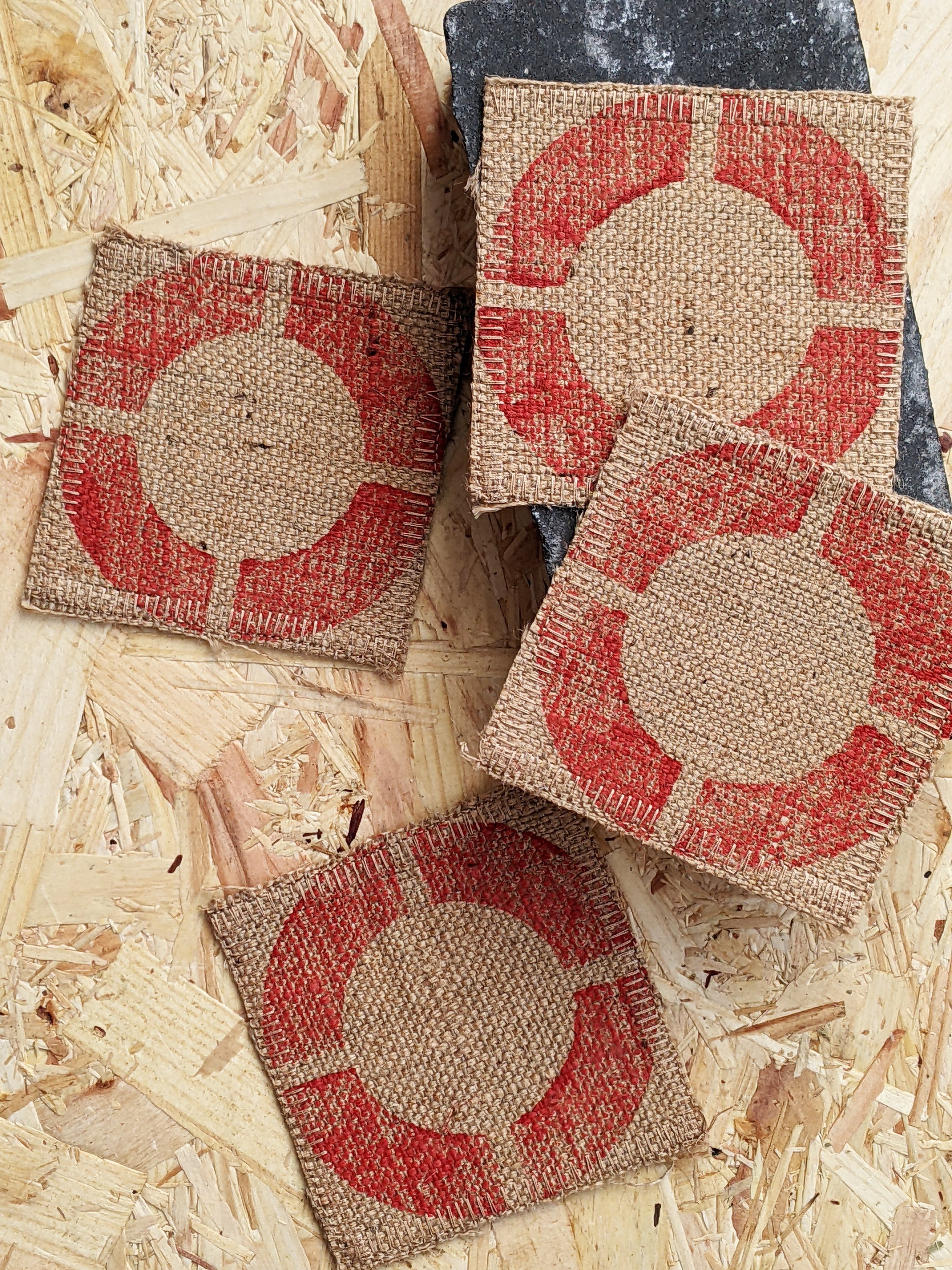 red circular geometric industrially inspired motif on set of fabric coasters