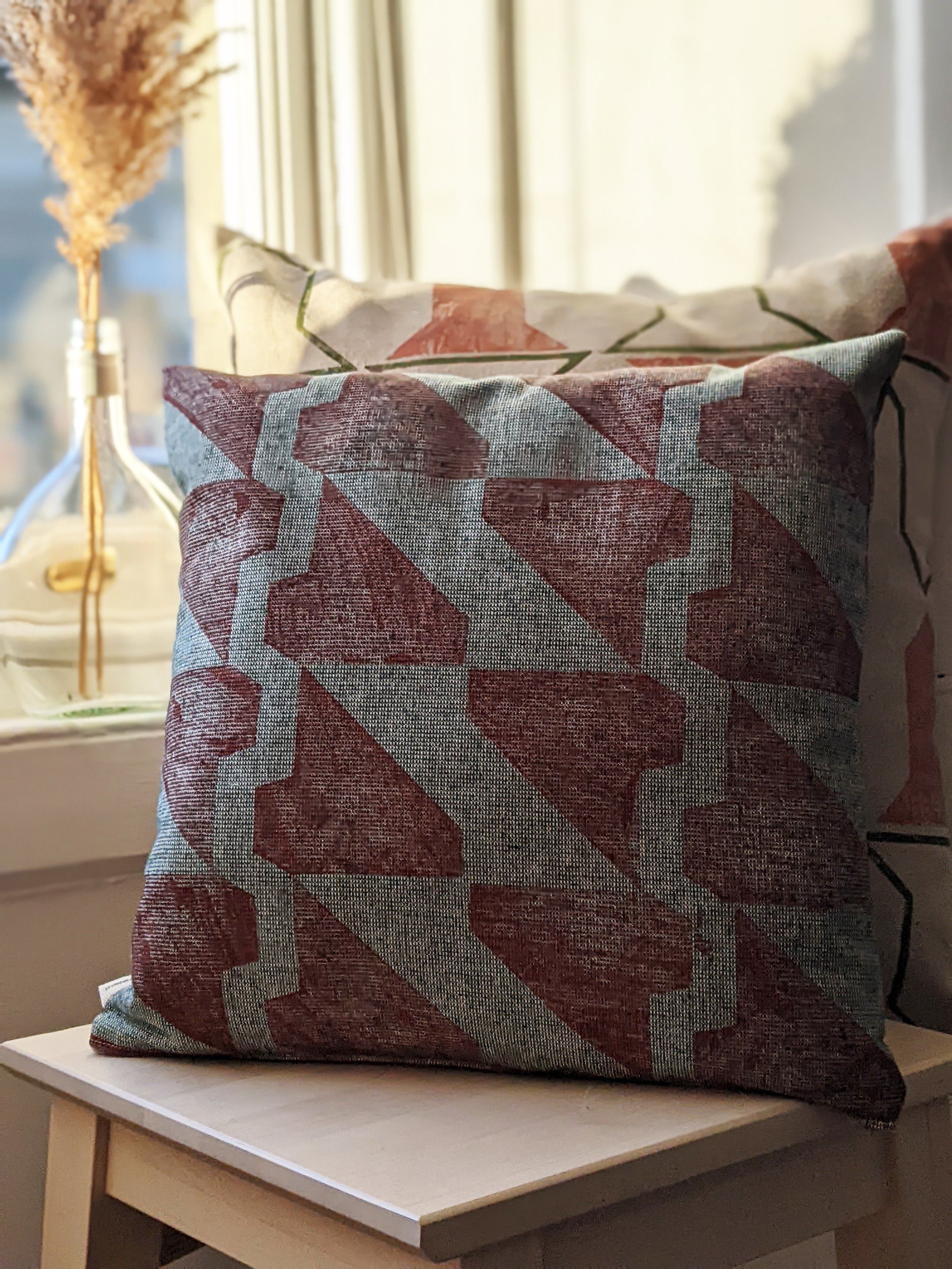 dark terracotta print on tactile green fabric on cushion designs