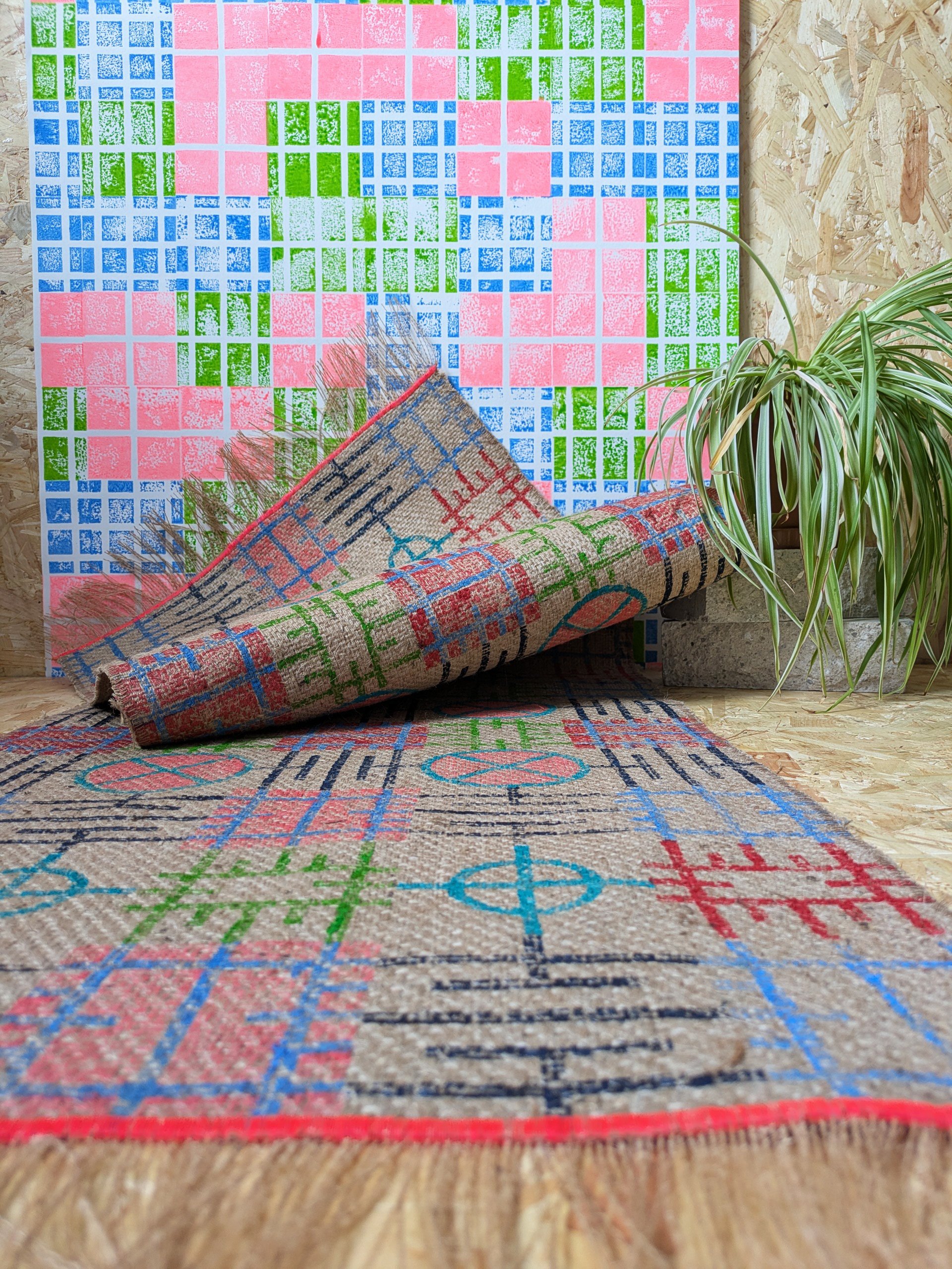 studio scene with bright wallpaper and colourful block printed jute rug in graphic grid pattern