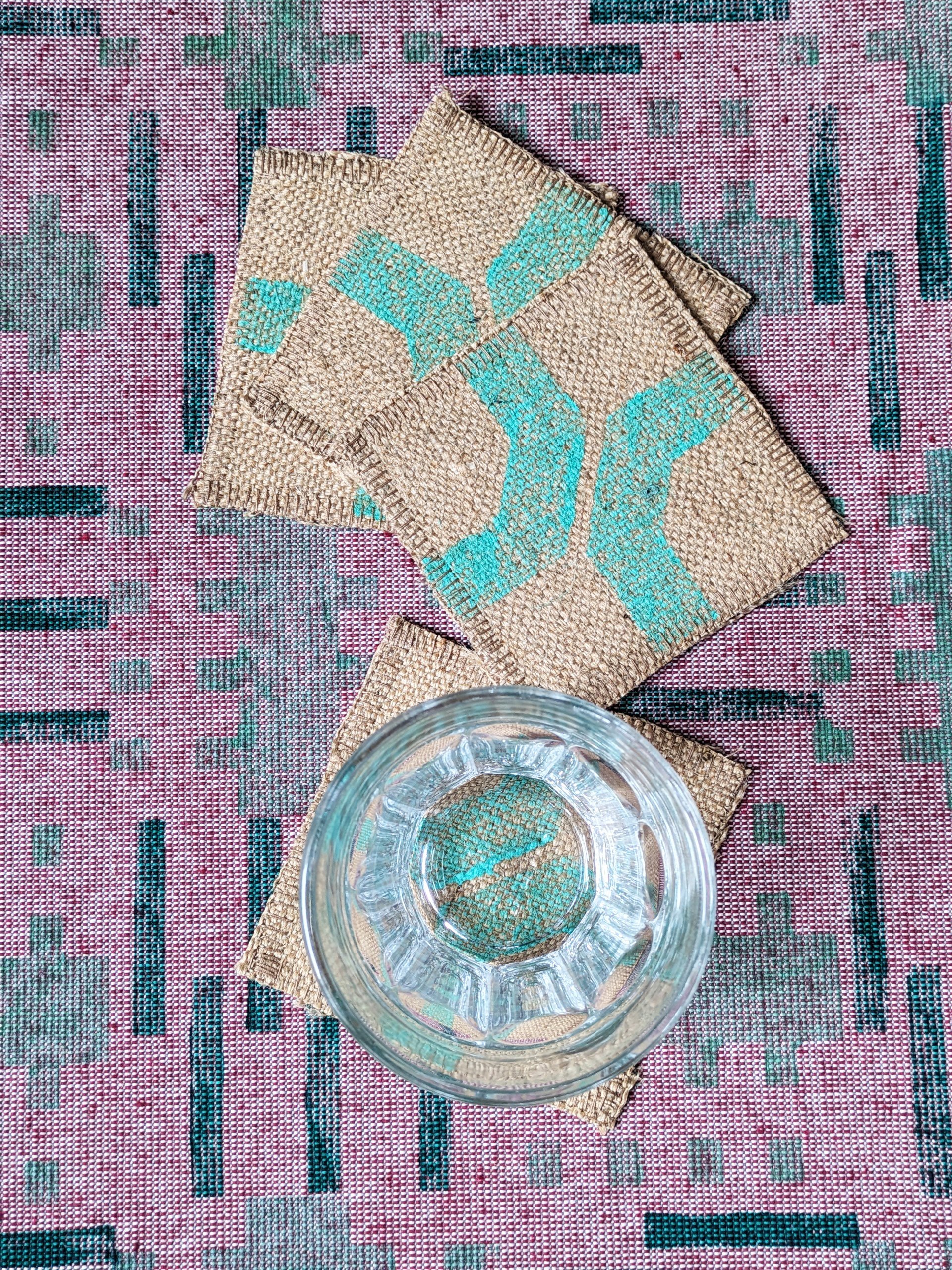 table scene with jute coasters in mint green and red tablecloth in brutalism inspired pattern