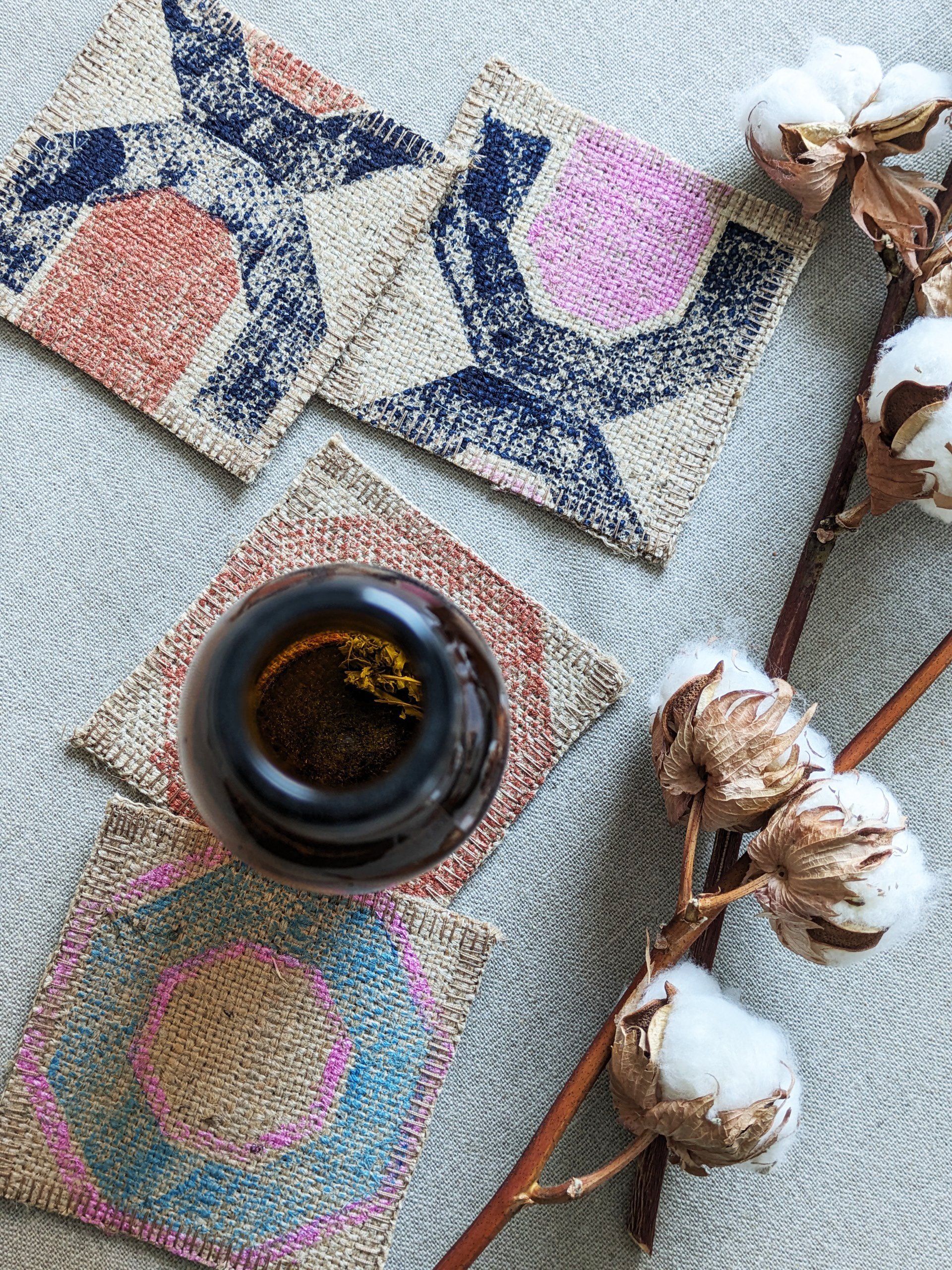 geometric print on modern rustic jute coasters in copper, pink and blue colours with beer bottle