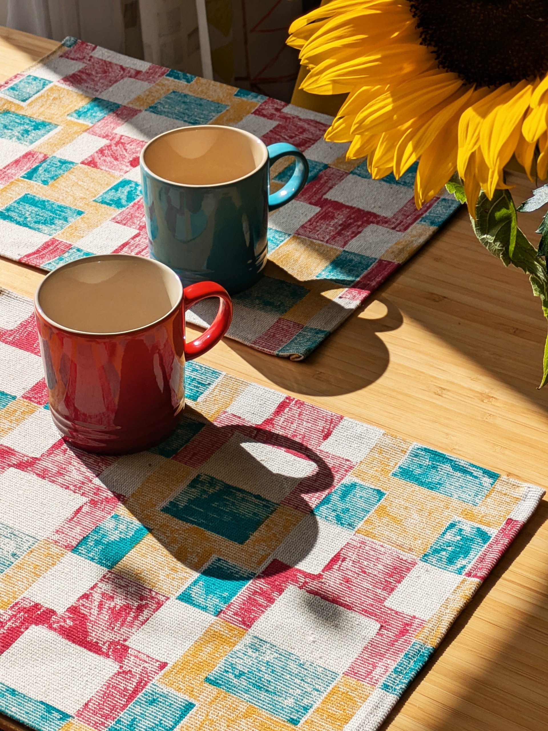 sunlit kitchen table with bold, colourful placemats in geometric abstract pixel-inspired pattern