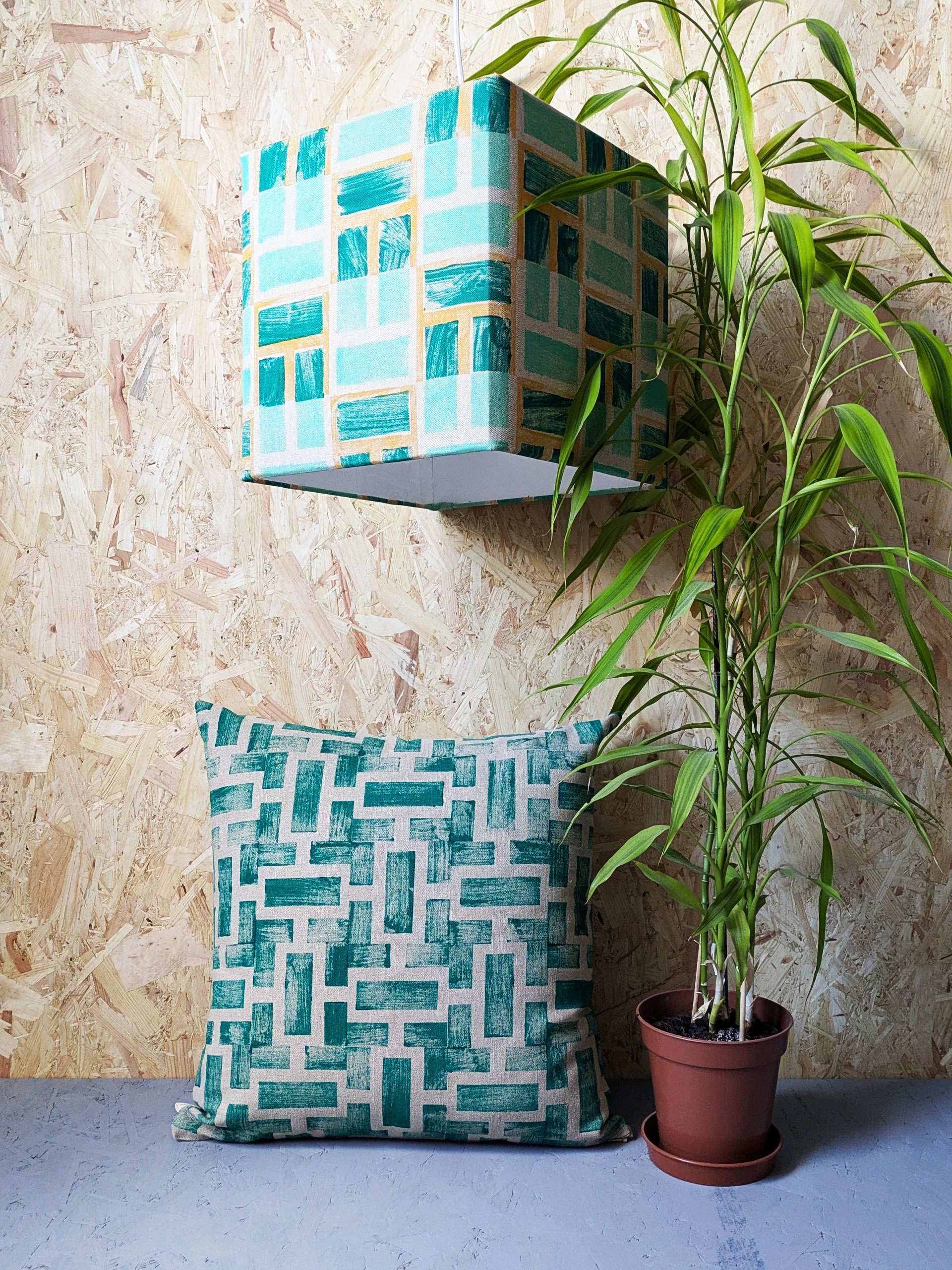 tropical interior design scene with cubical geometric lampshade and lush green luxury linen cushion