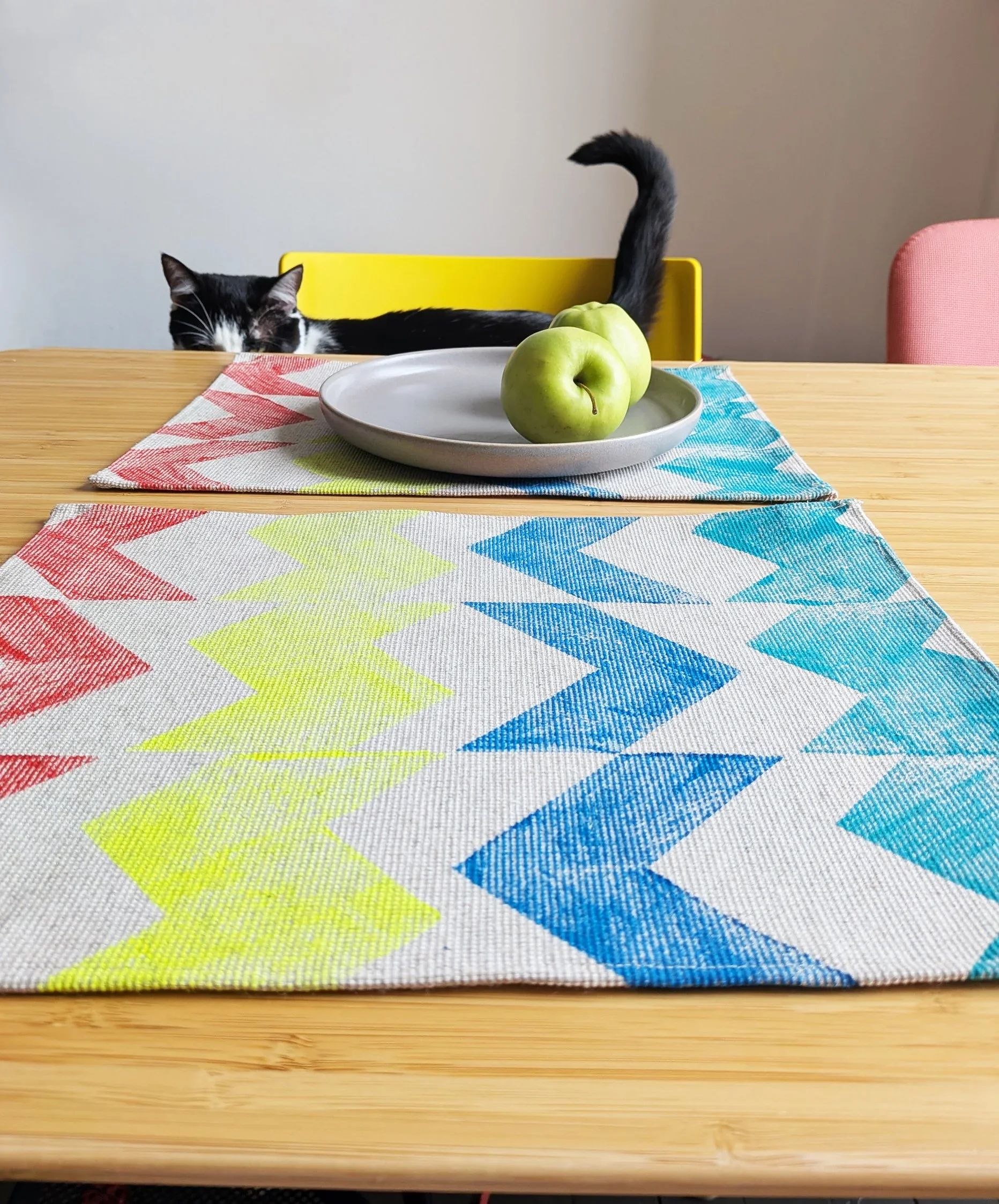 kitchen table with zig-zag printed vibrant colourful geometric place mats and curious cat