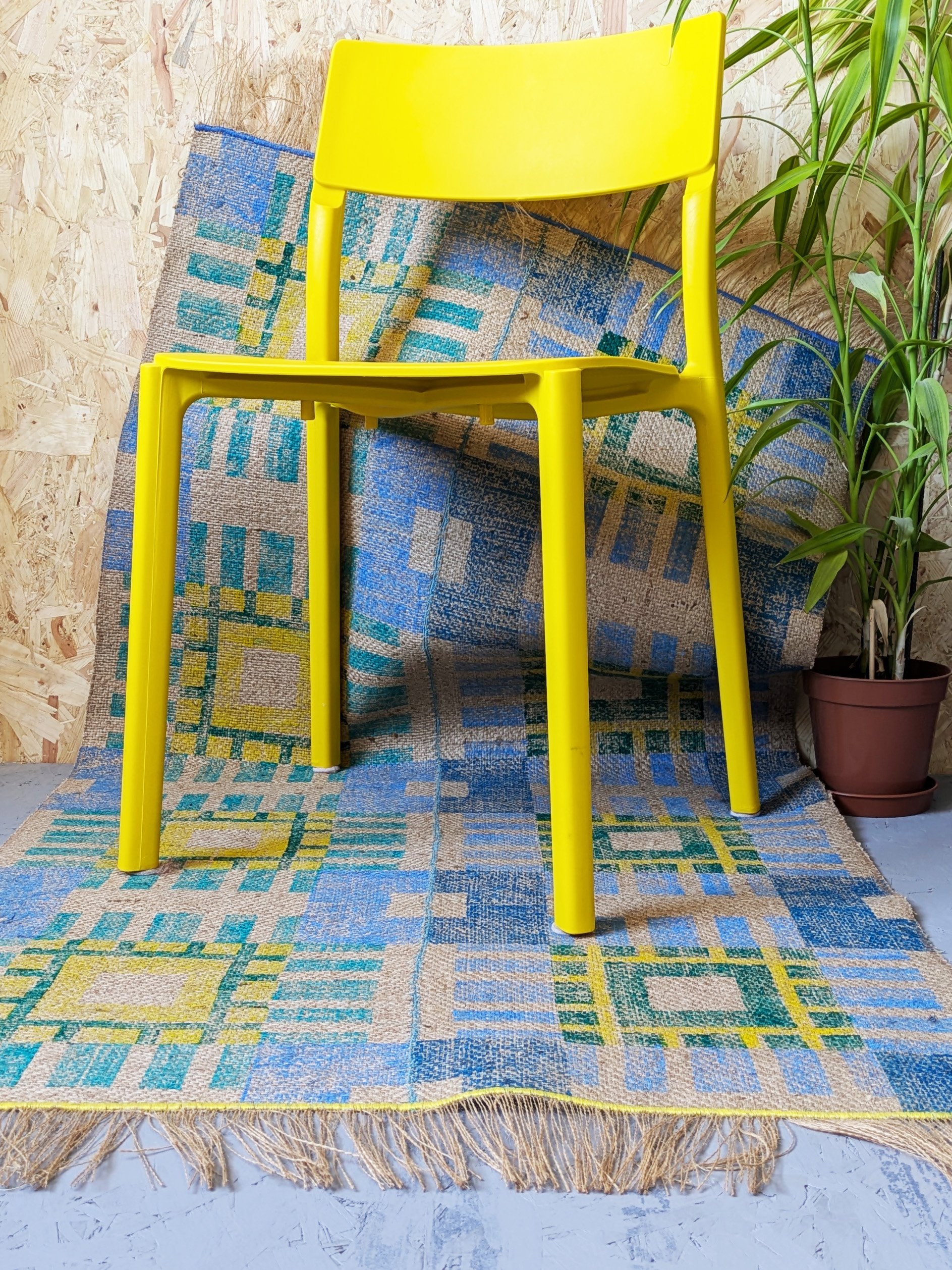 colourful interior scene with yellow plastic chair and bold contemporary rug in geometric pattern in cool colours