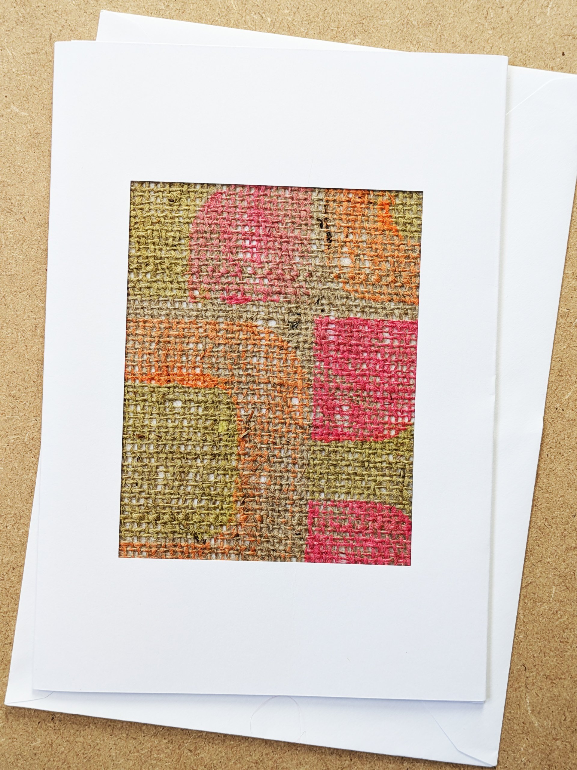 neon pink and orange print on jute fabric piece framed in white postcard frame and white envelope