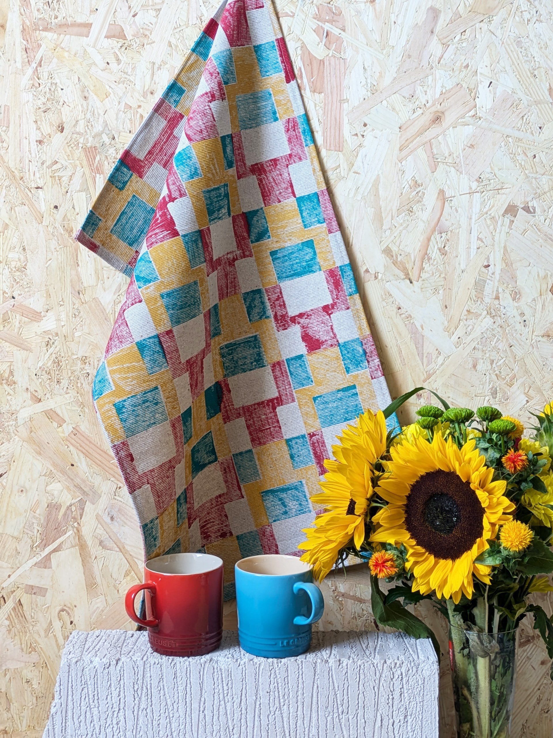 hand printed kitchen towel hanging on studio wall in pixel-inspired colourful abstract geometric design