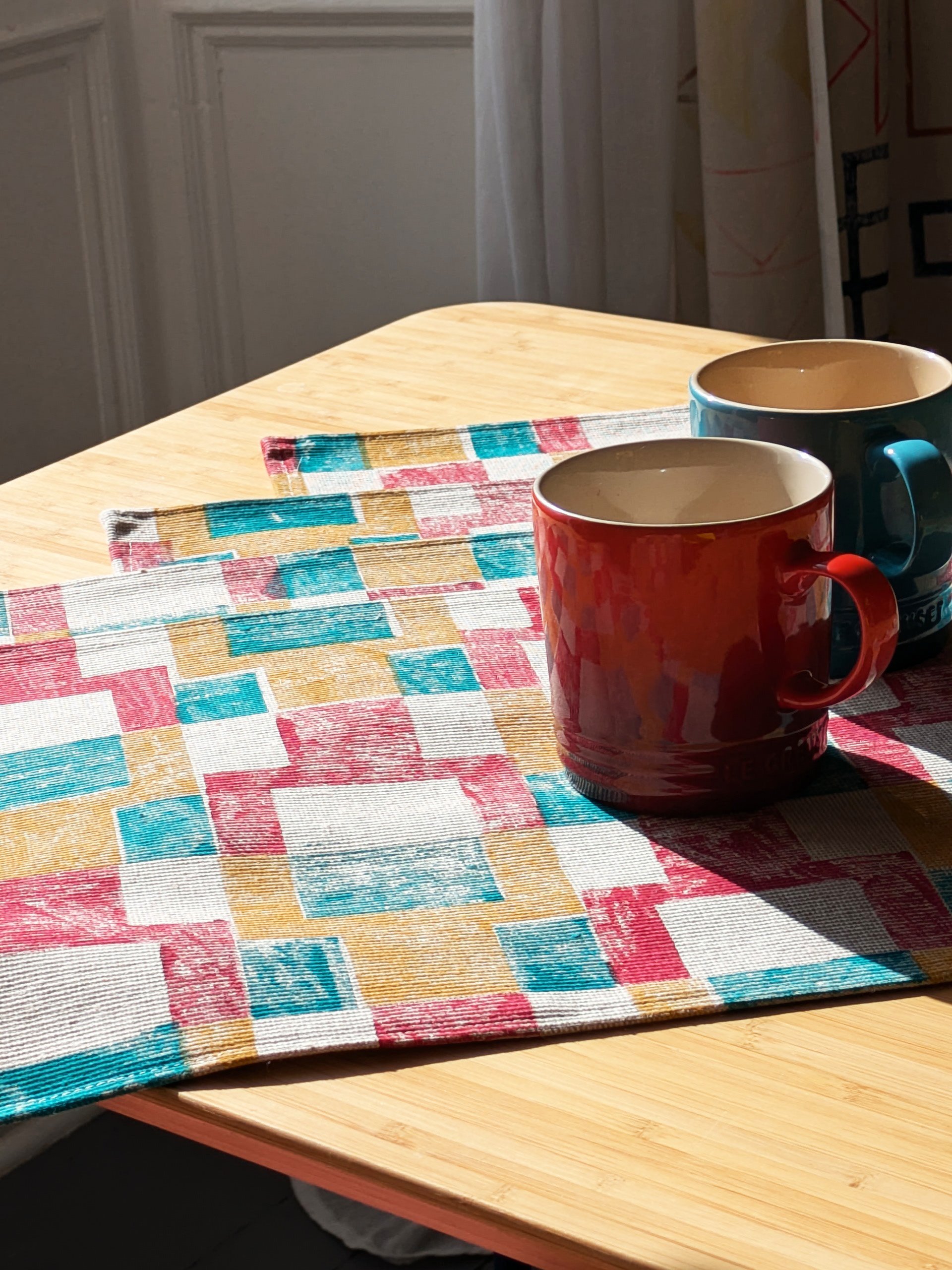 sunny kitchen scene with four colourful place mats with contemporary abstract bold retro pixel prints