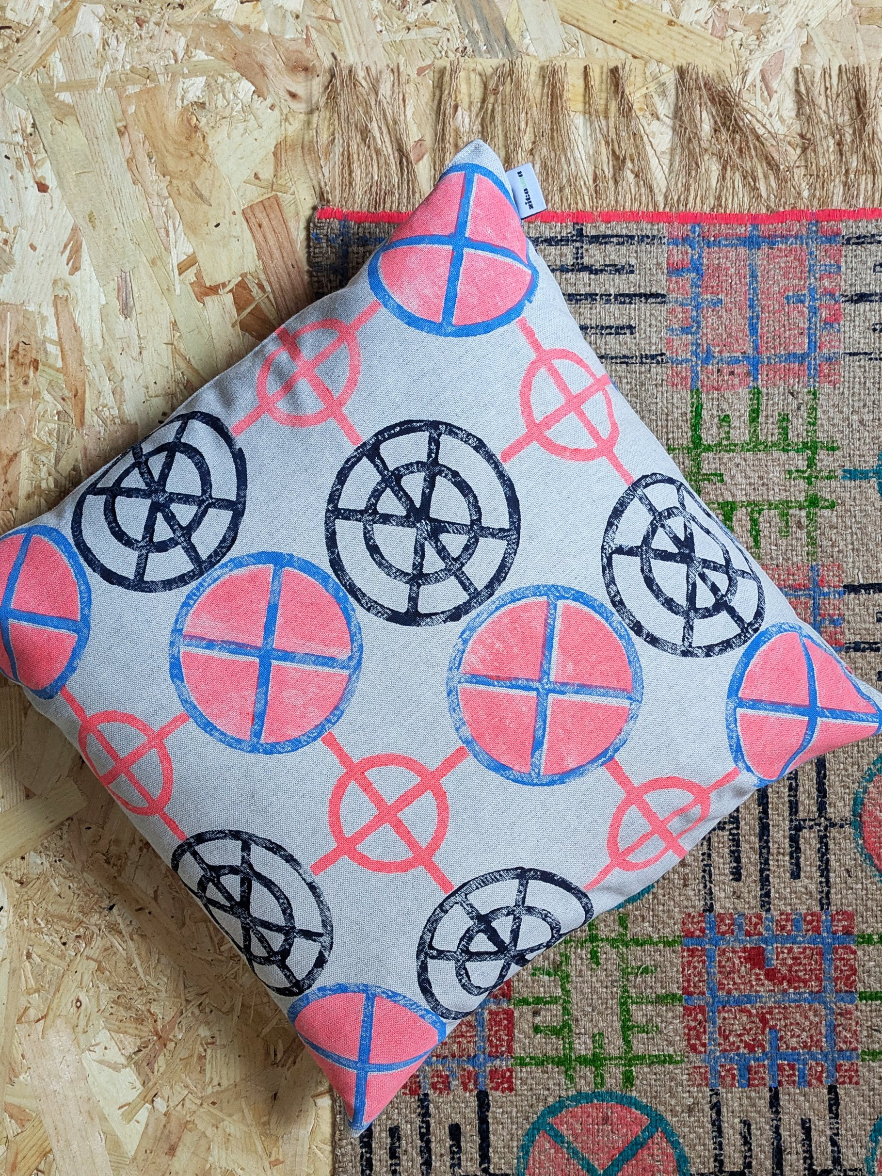 cushion in bright neon pattern on floor with geometric printed jute rug