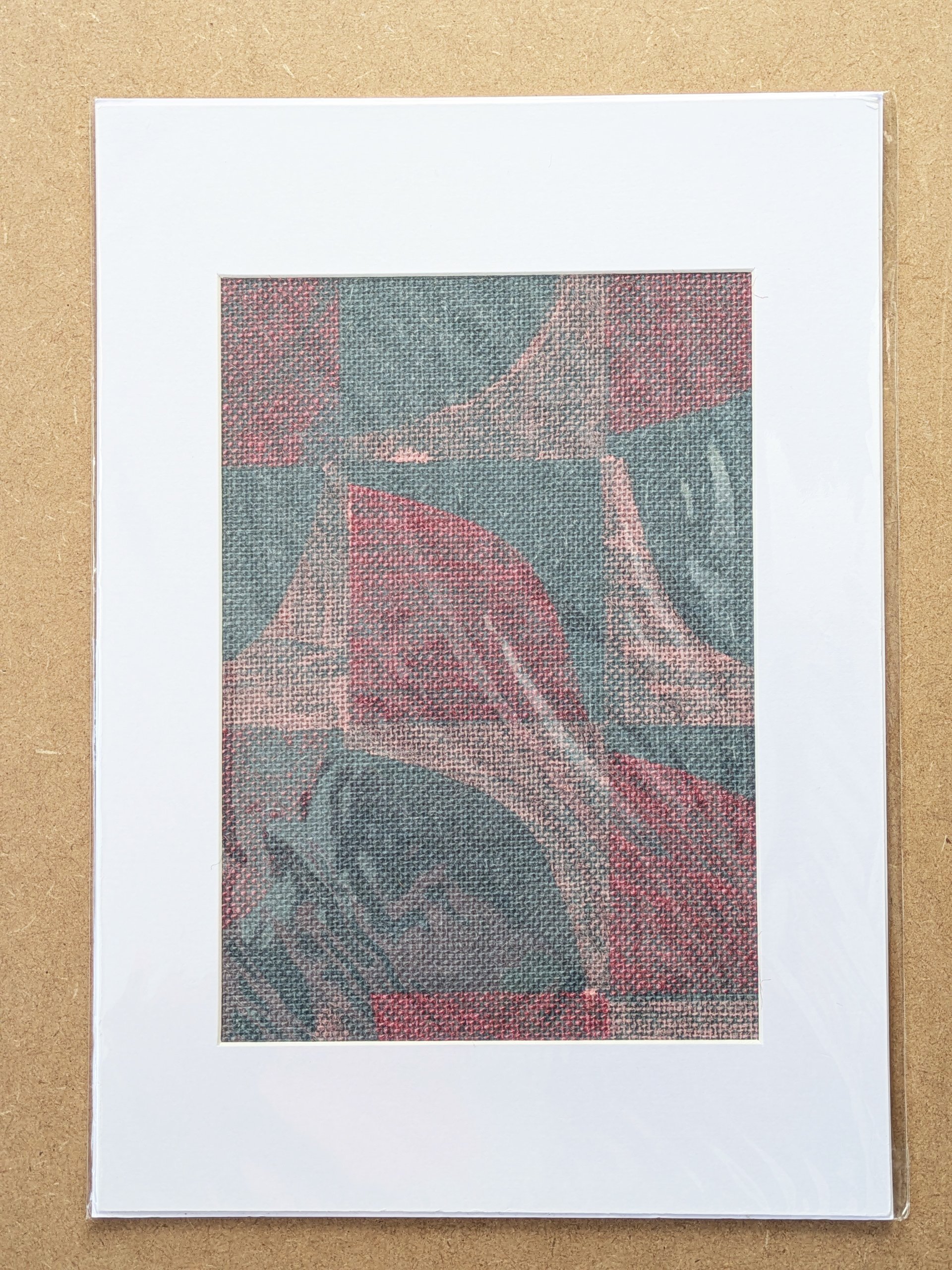 abstract geometric print in pastel colours, hand block printed on blue grasscloth wallpaper, framed in A3 mountboard