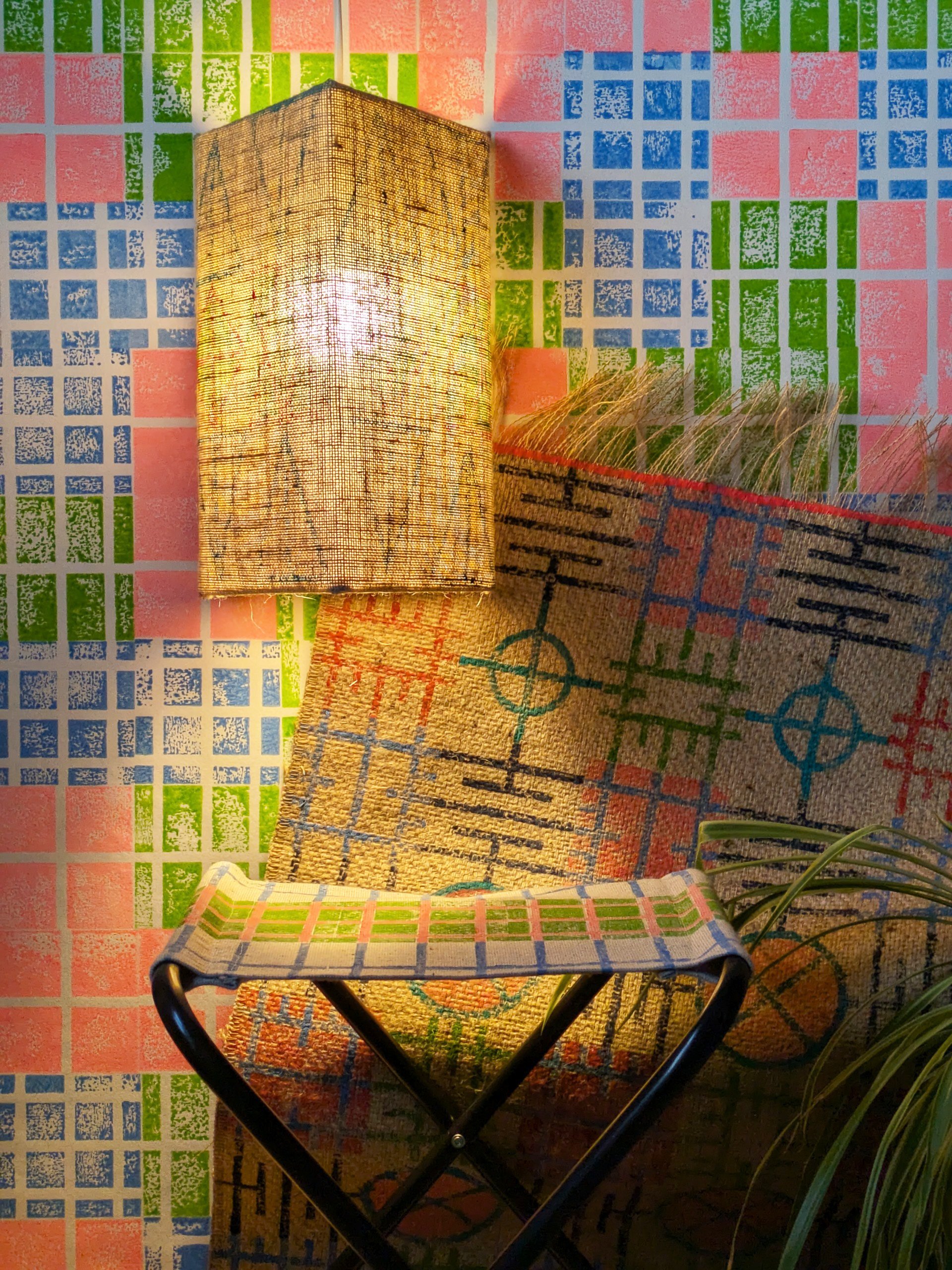 bold interior scene with bold grid-pattern wallpaper and rug with cosy ambient jute lampshade in triangular print