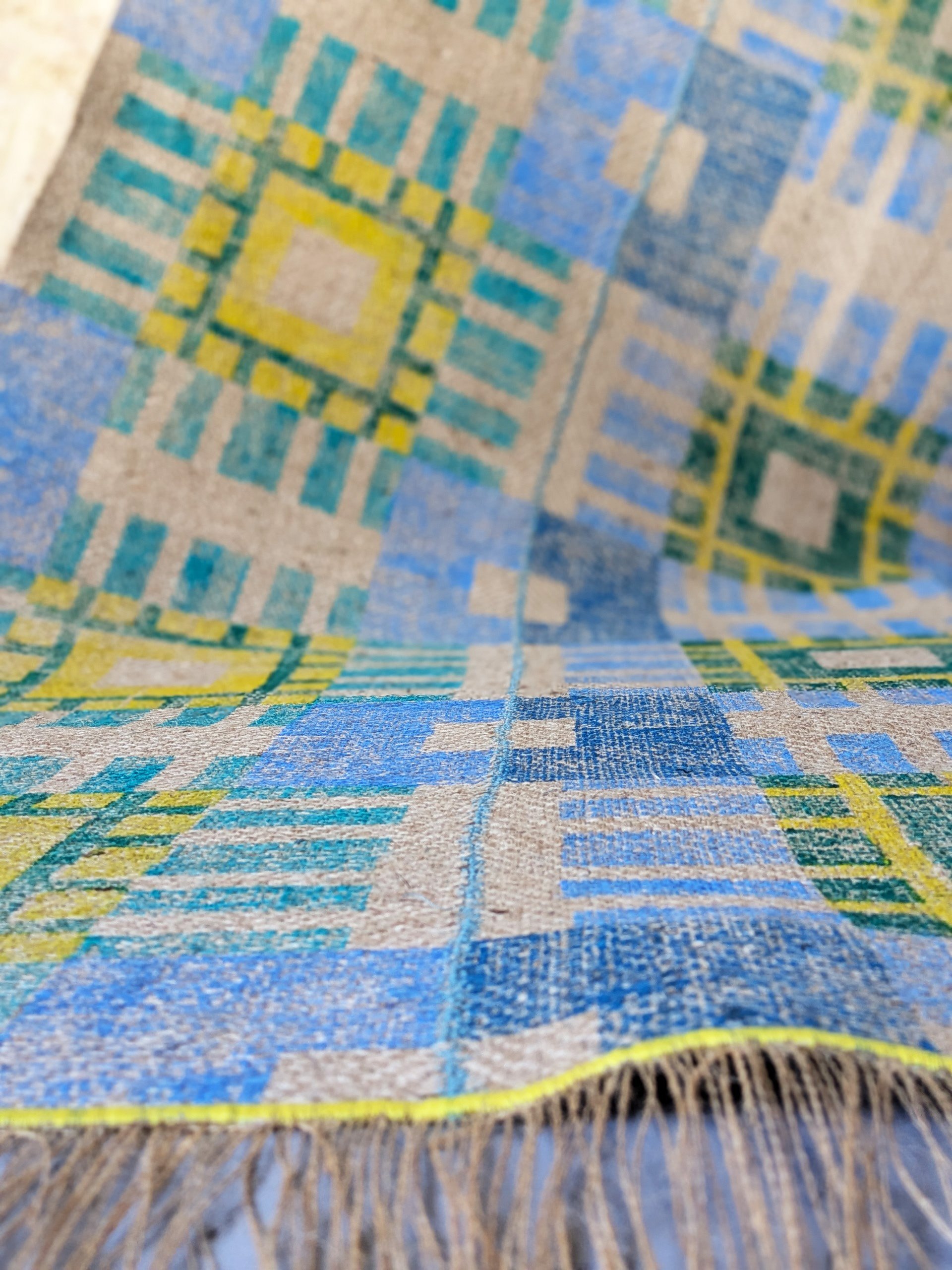 close-up detail of hand block printed rug in large check pattern stitched together in blue yellow and green colours