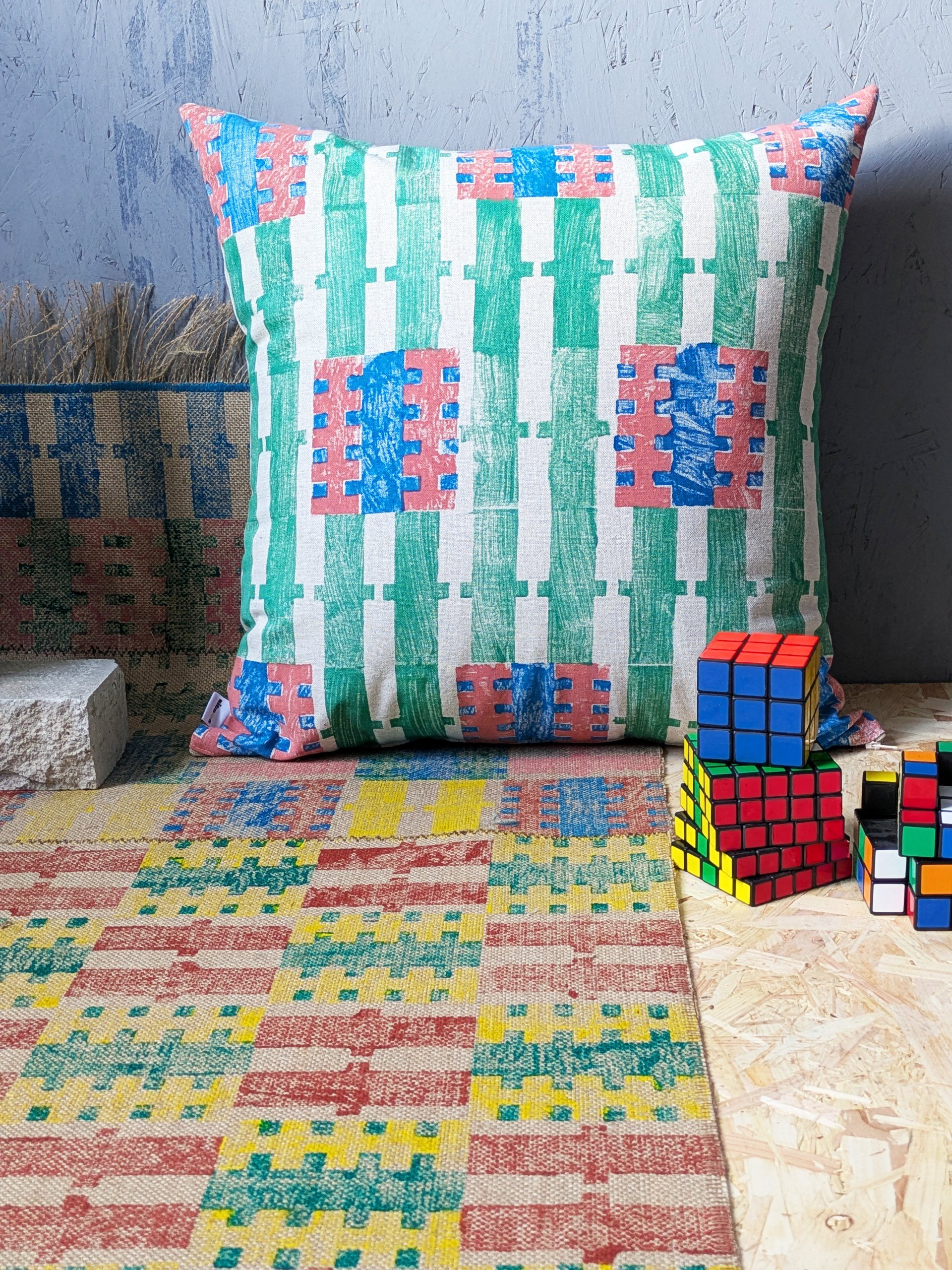 dopamine decor scene with striped b-old cushion and checked and striped rug with colourful toys