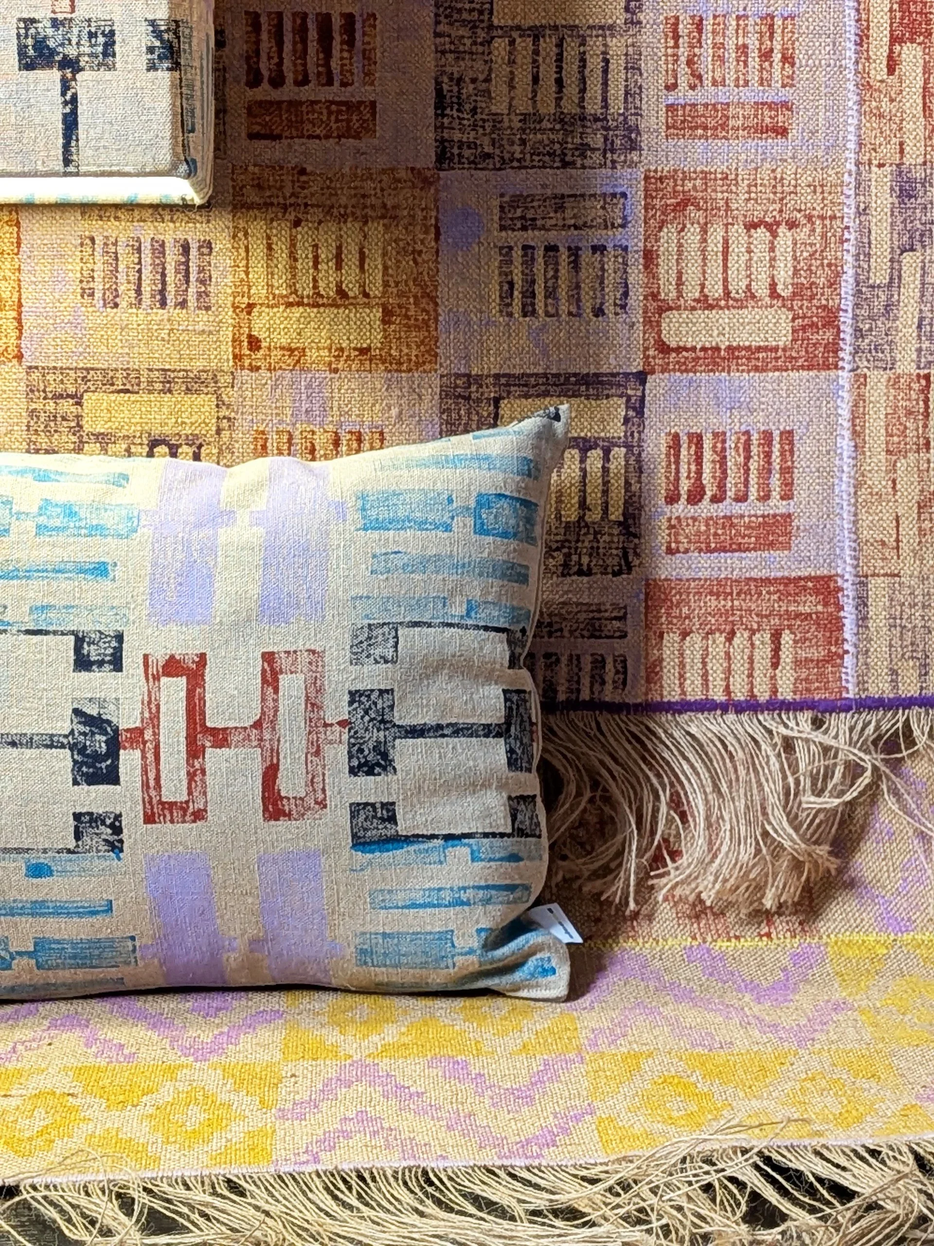 warm and cosy interior scene with close-up details of tactile textiles with architecture inspired geometric patterns