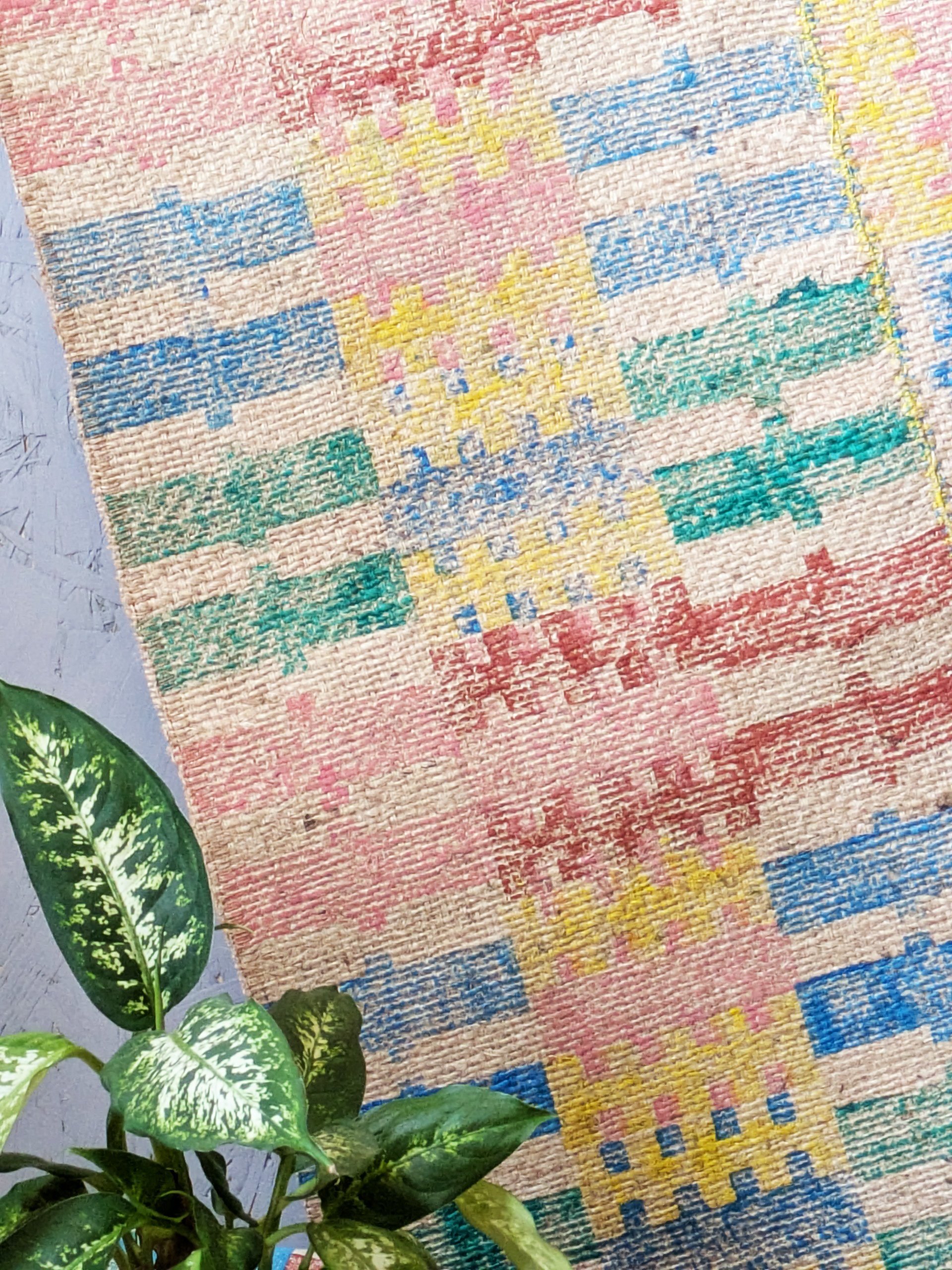 close-up detail of bold stripe print on jute rug with pastel pink and yellow