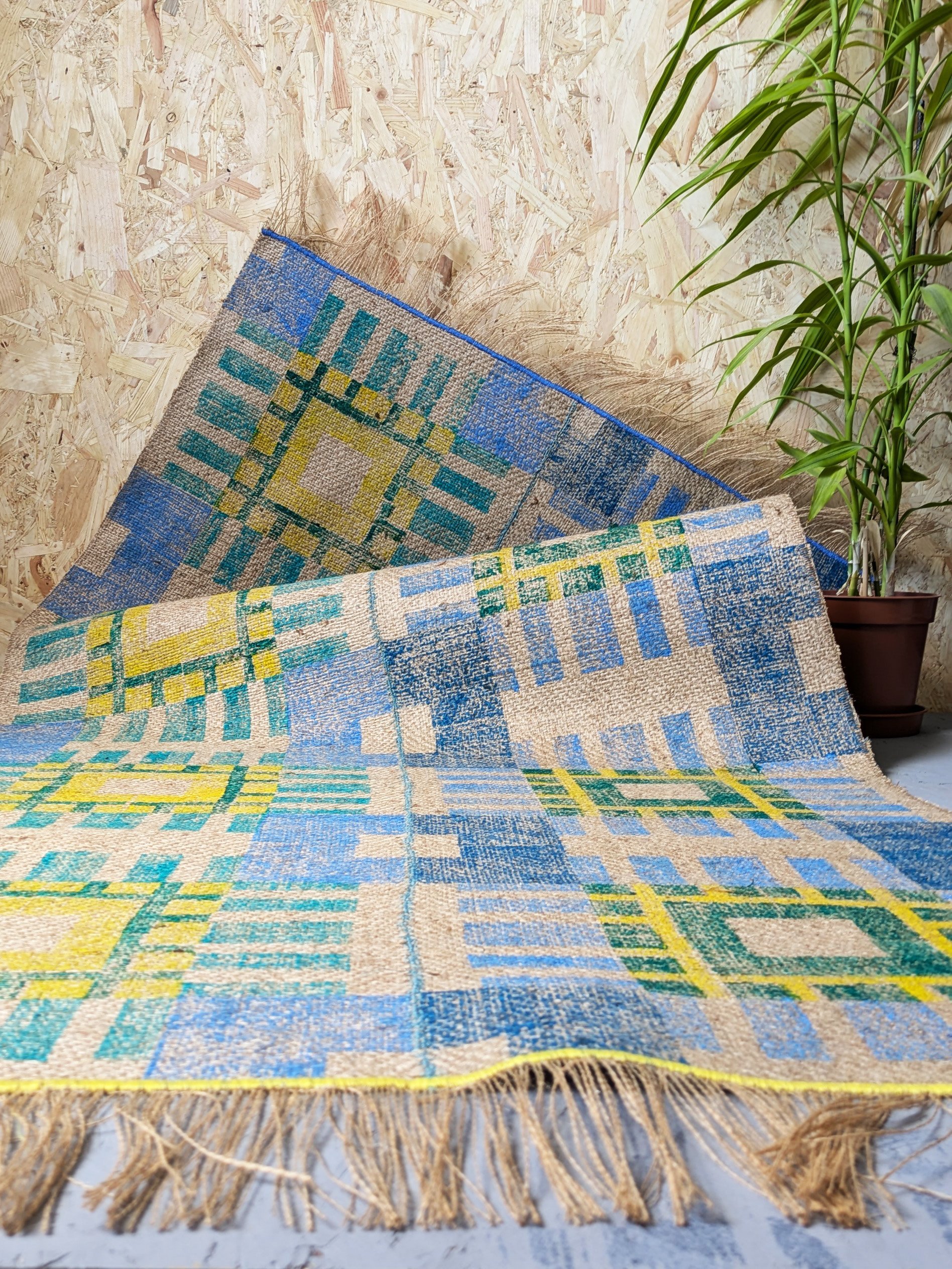 geometric printed rug in large scale tartan check pattern in modern cool colours - yellow, green and blue in a contemporary studio setting