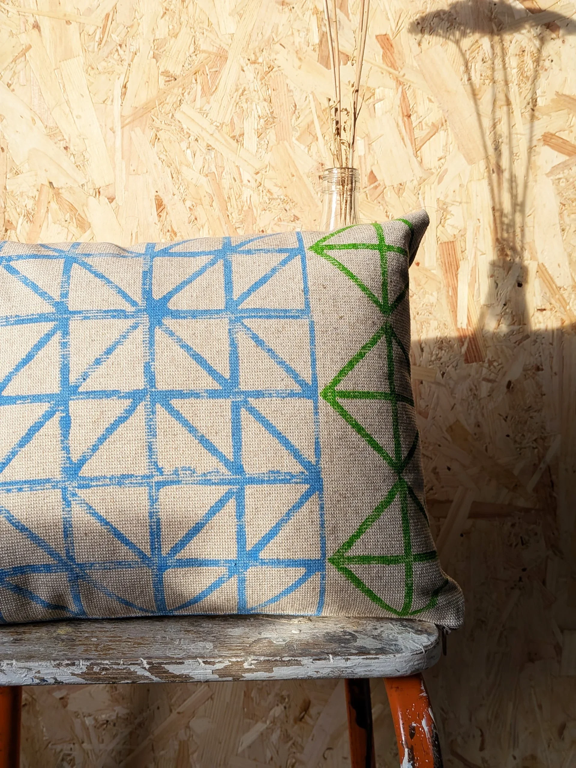 contemporary sun-lit interior with fresh blue and green triangular geometric pattern block printed on small cushion