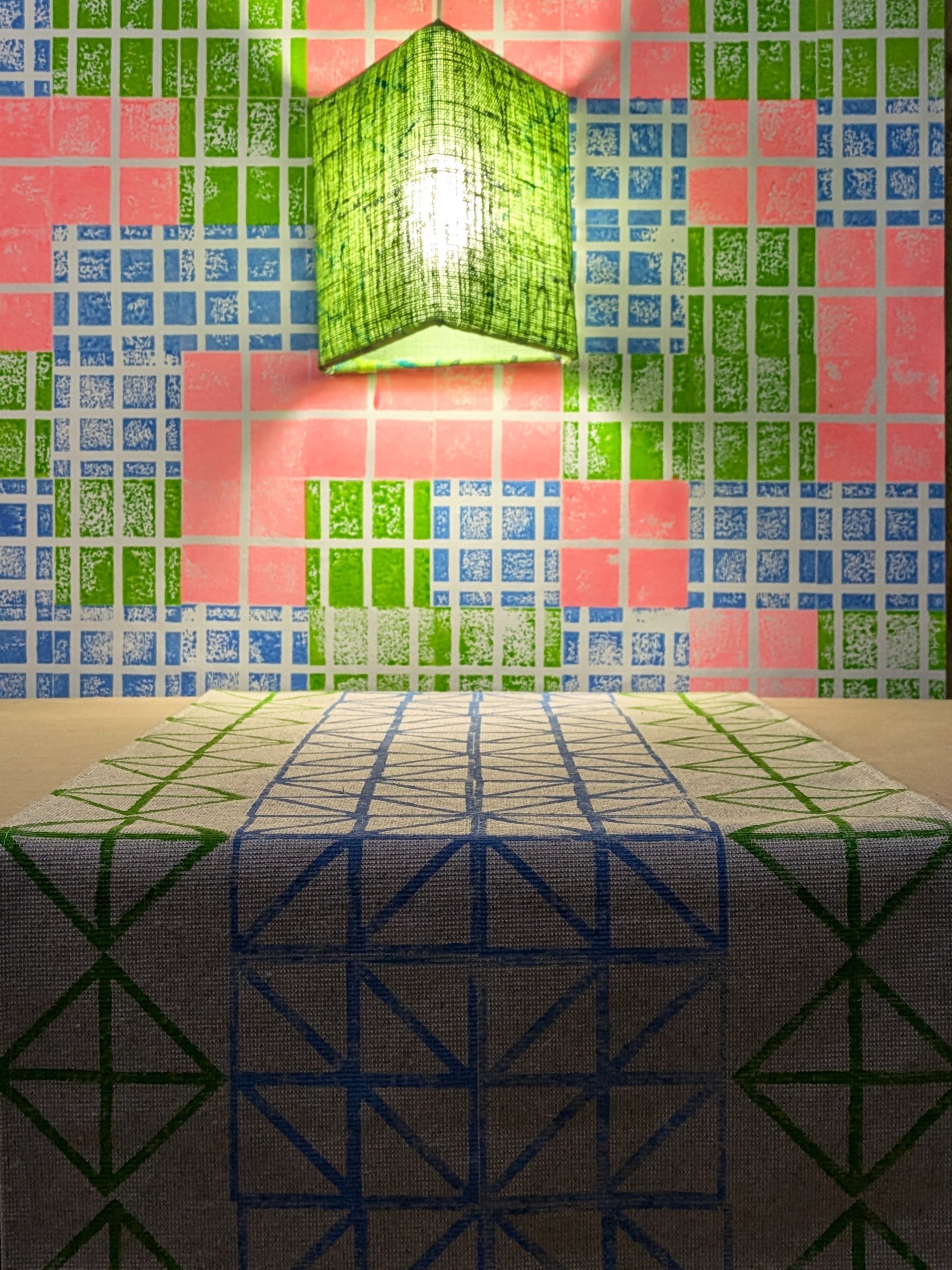 bold graphic patterns on studio wall with bright green triangular lampshade and geometric printed table runner