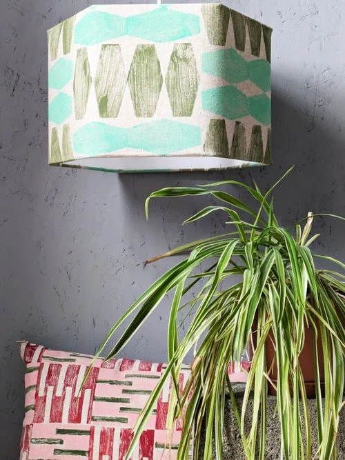 hexagonal lampshade in bright colours in abstract geometric print with small bright red cushion