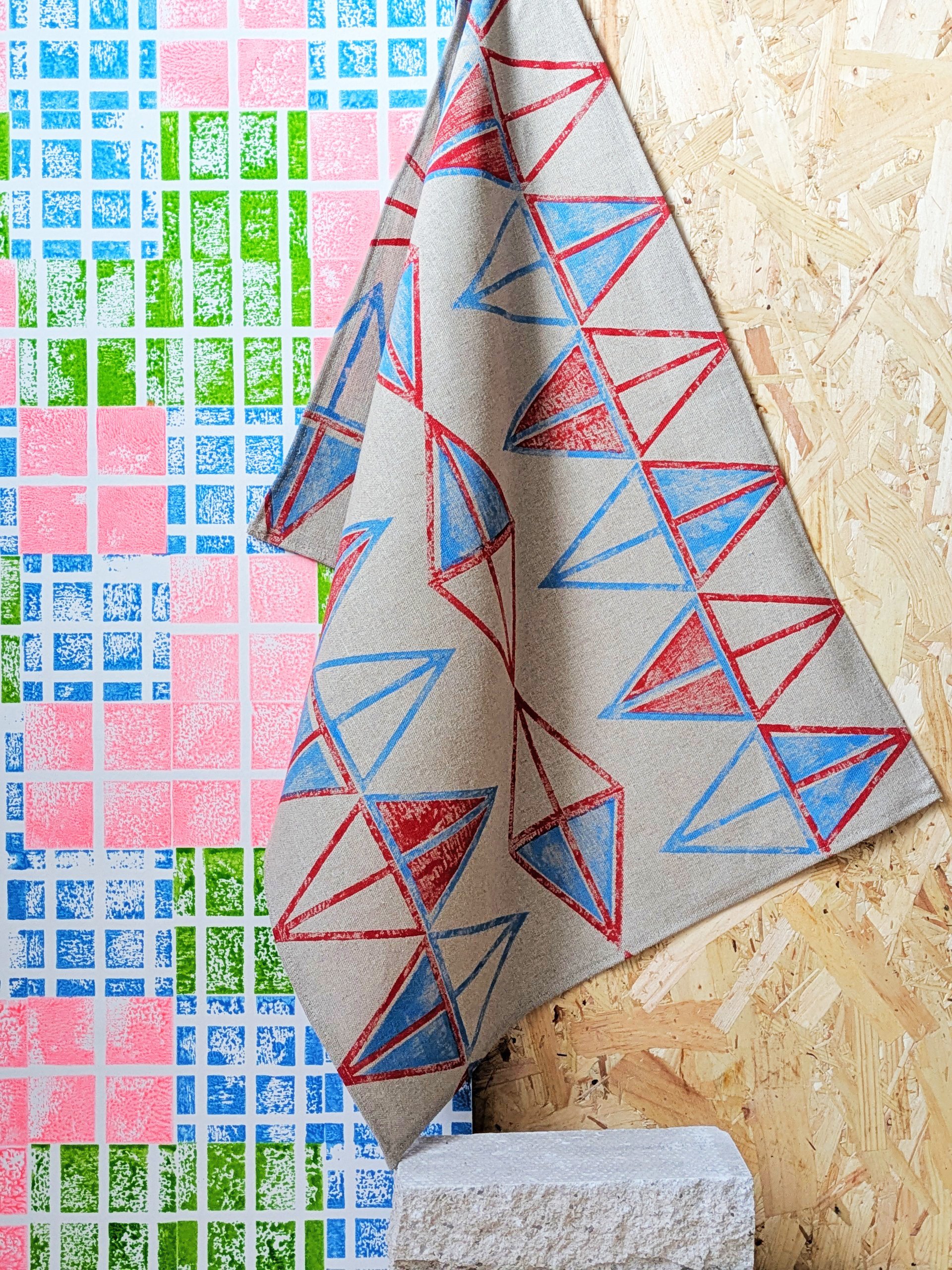 colourful studio scene with bright wallpaper and playful pattern on teatowel hanging on wall