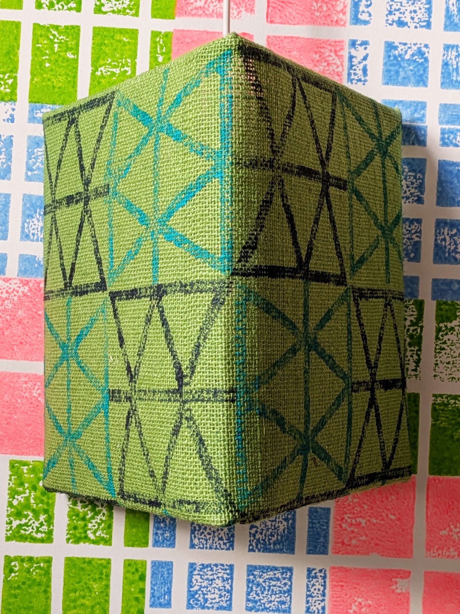 triangular shaped green lampshade on bright wallpaper