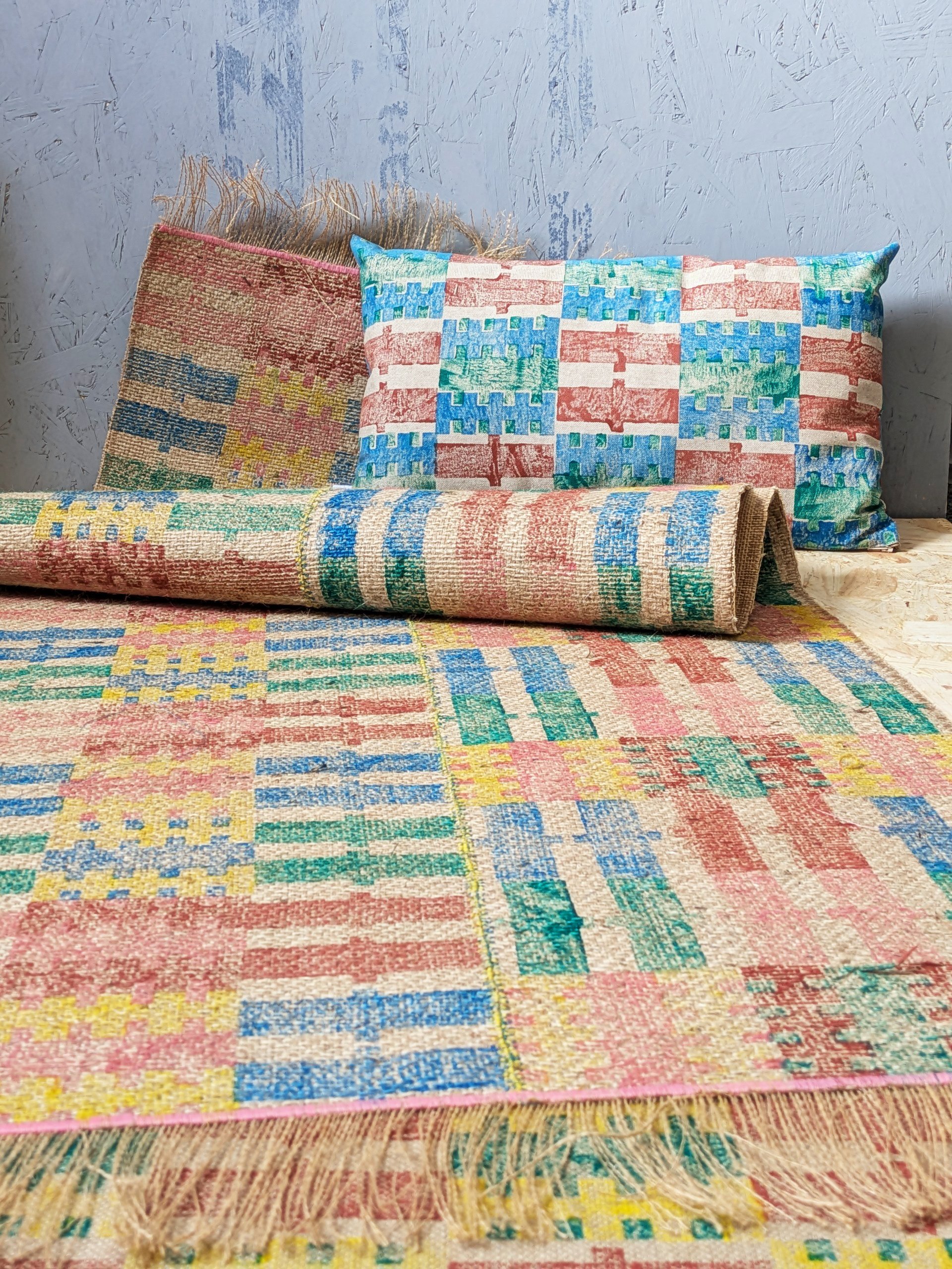 studio scene with bold striped rug on floor and colourful abstract striped rectangular cushion