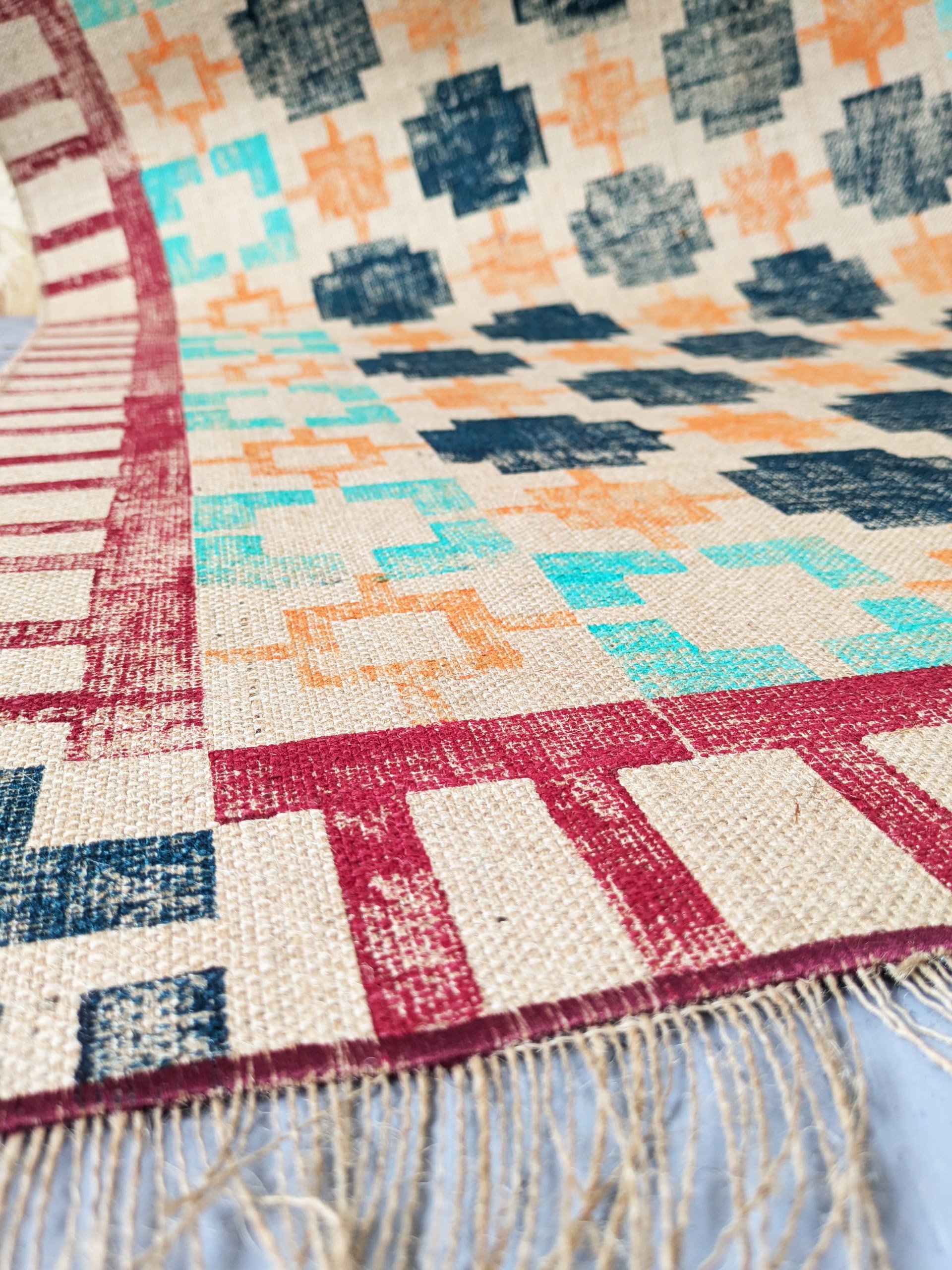 close-up detail of bold design on hand block printed jute rug in geometric pattern and warm cosy colours