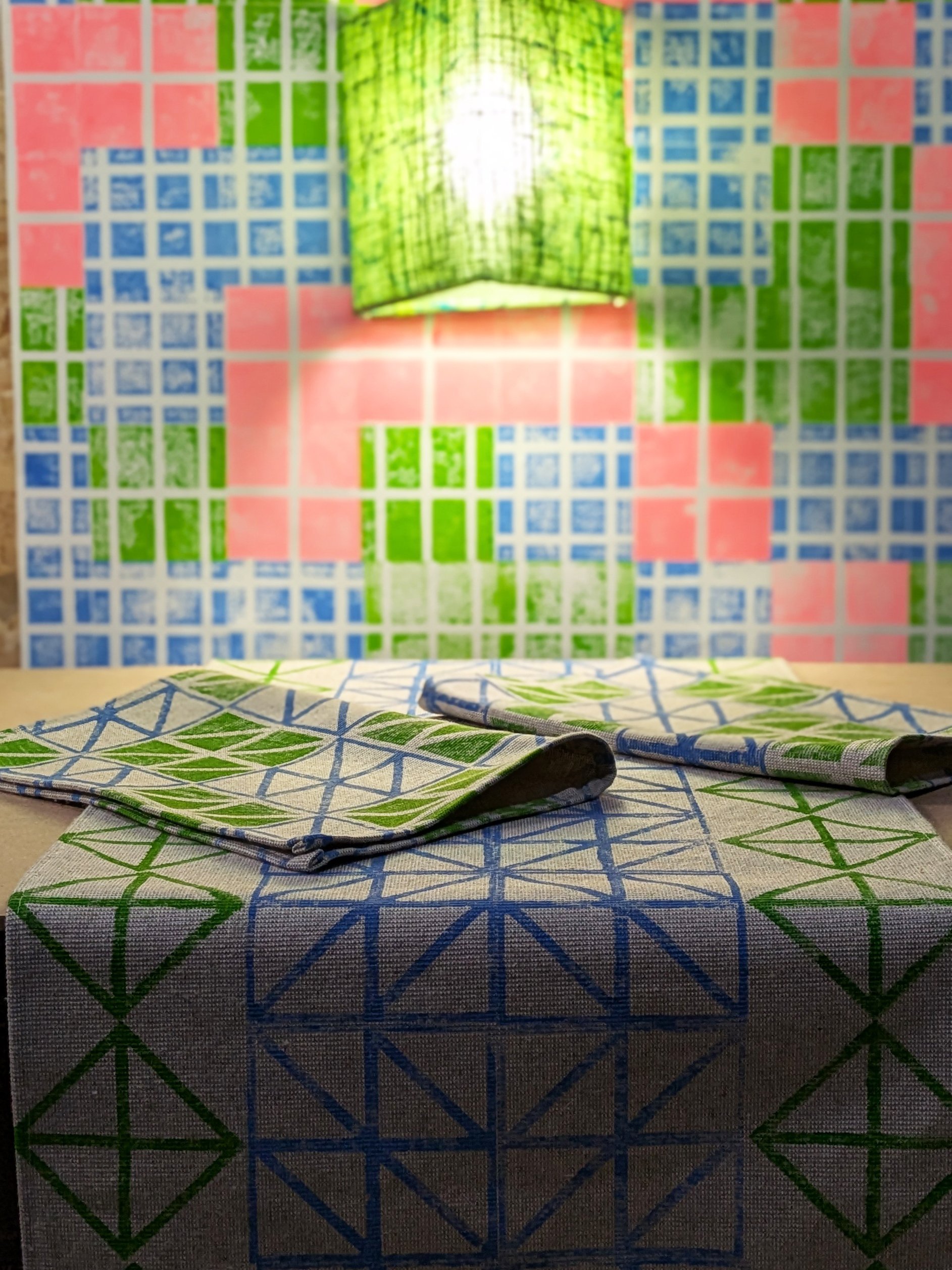 cosy studio scene with table set with table runner and folded place mats in bright colourful block printed patterns