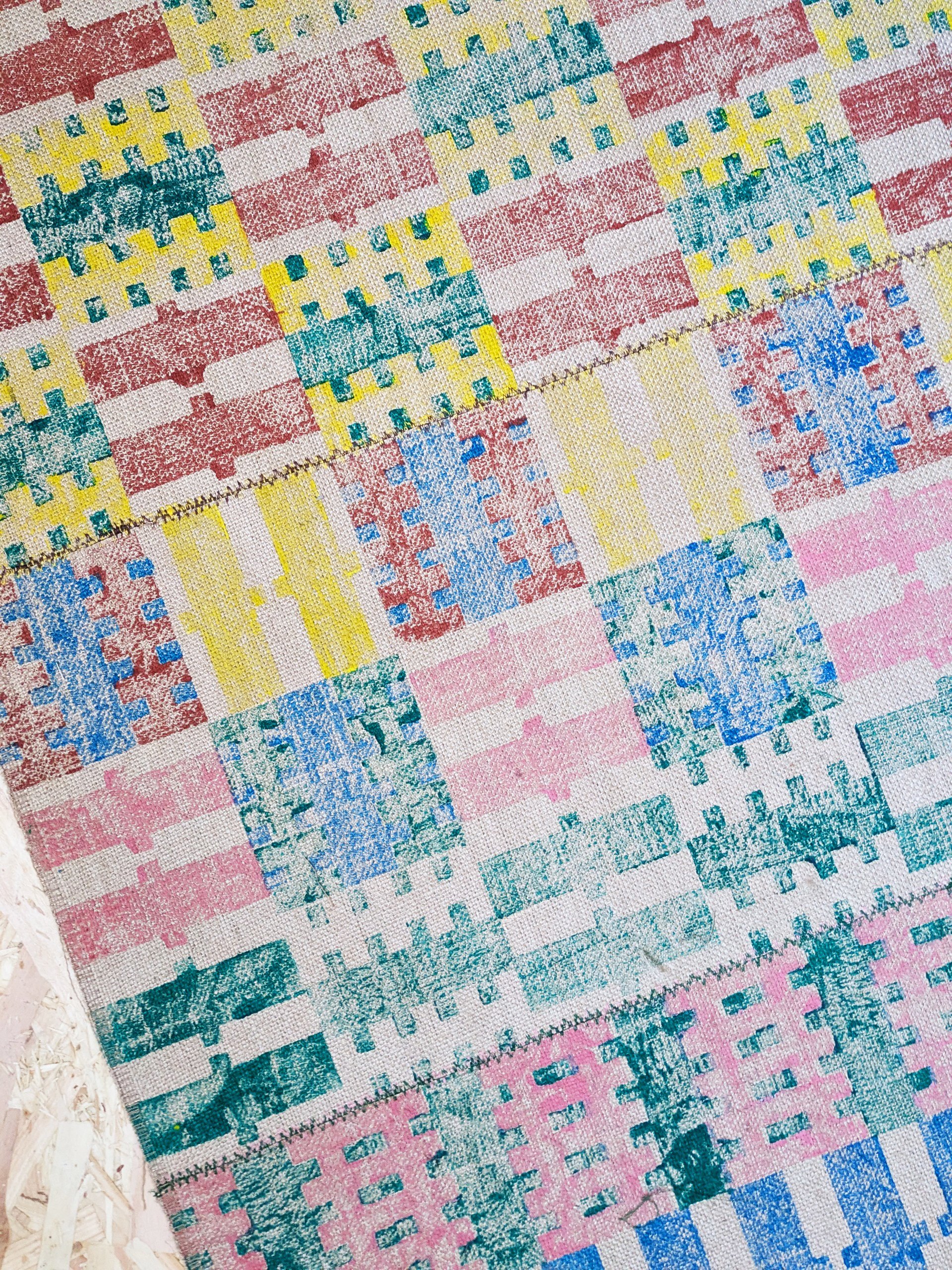 close-up detail of hand block printed stripe-check pattern in bold summery colours on jute rug