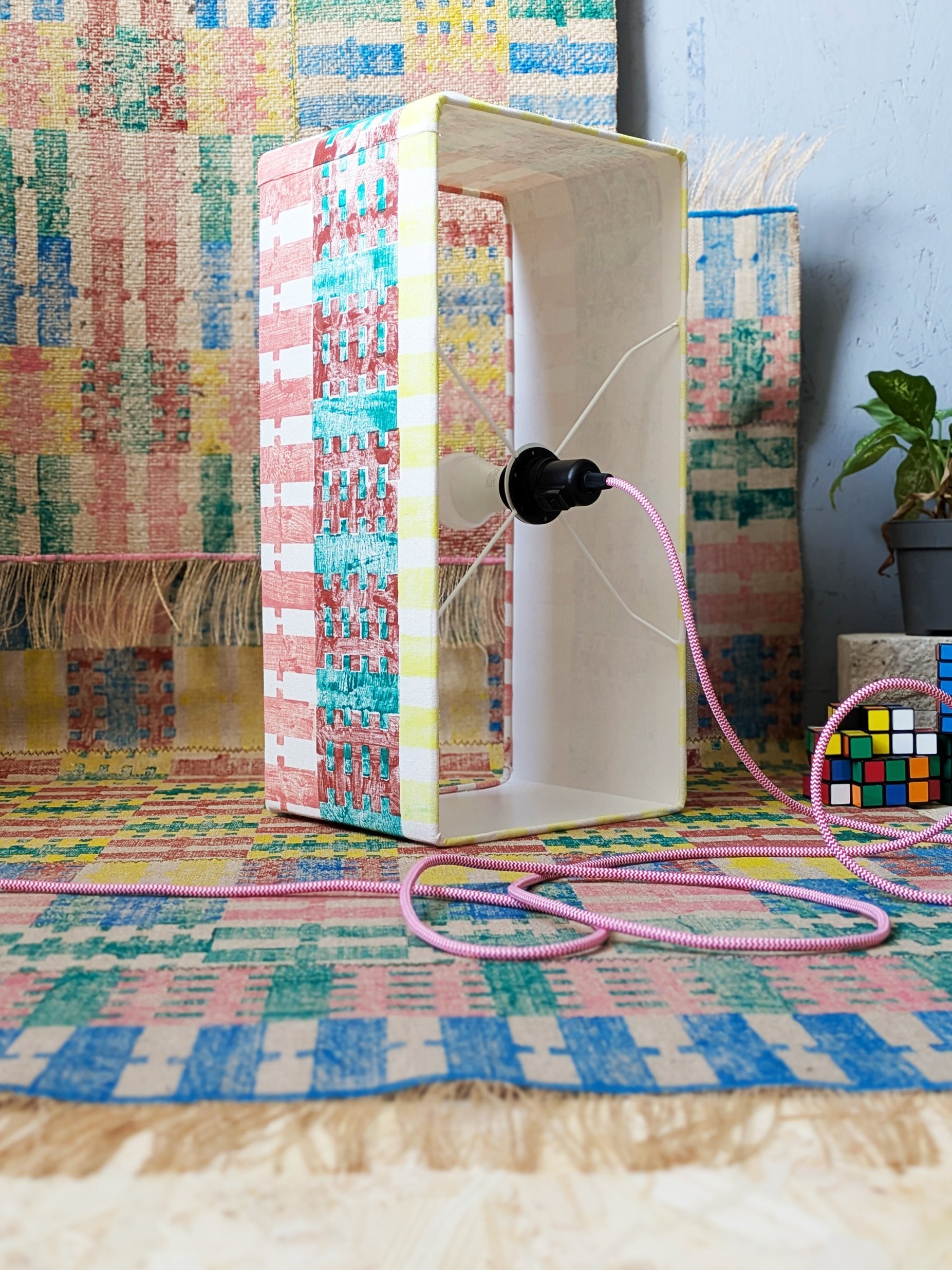 rectangular lampshade standing on colourful, striped rugs in dopamine decor interior scene