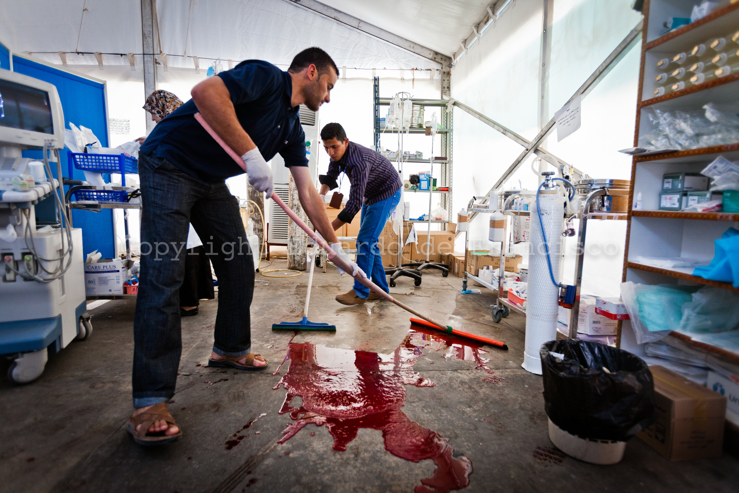  Workers at the emergency unit of Al Hikma hospital in Misrata clean a poodle of blood after a severely injured soldier was treated 