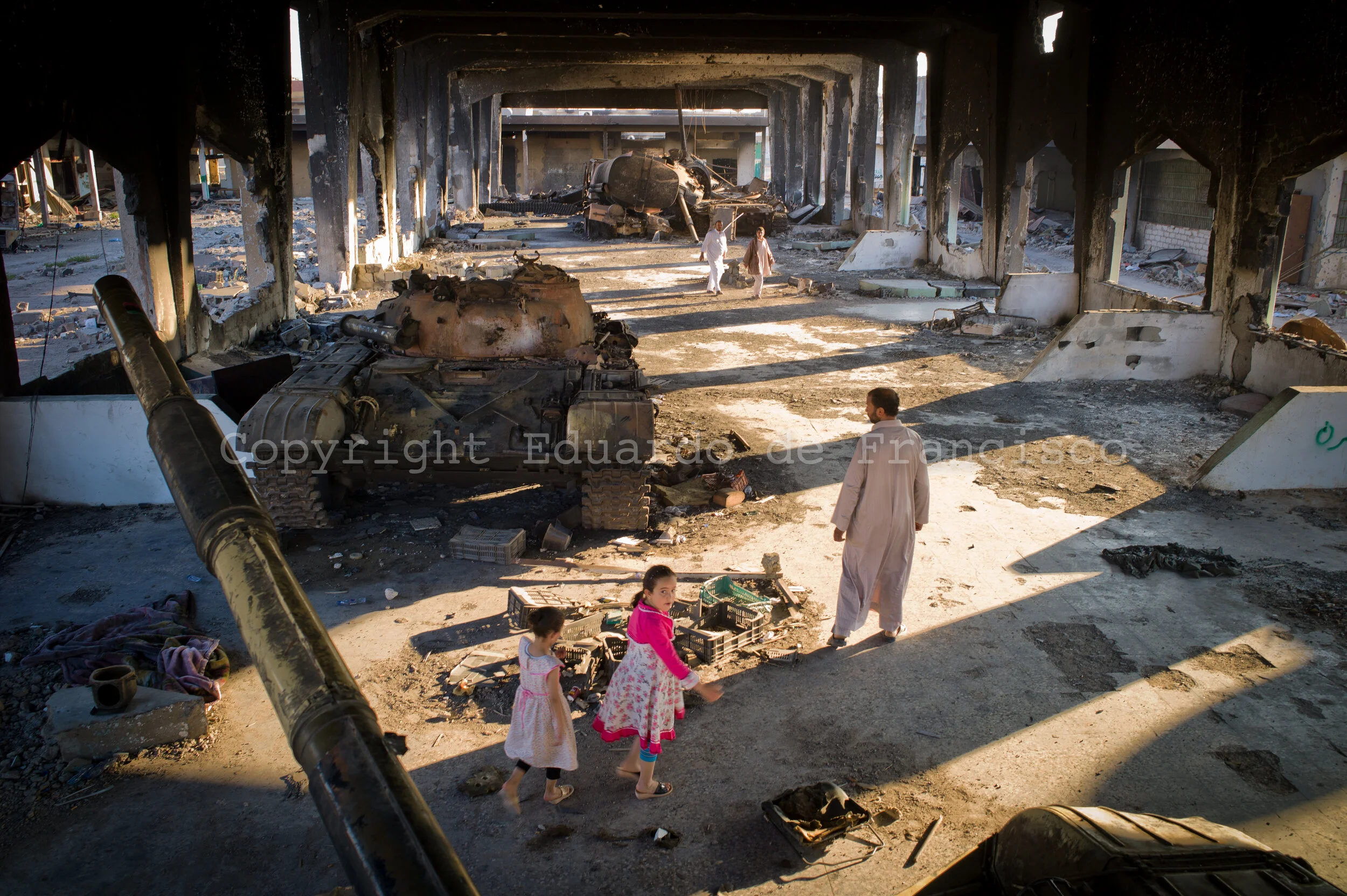 Misrata's families watch a group of tanks used by the infamous Khamis Brigade (commanded by one of Gadaffi's sons) to bomb civilian buildings in the center of Misrata. This building (a market before the war) was later bombed by NATO to destroy a tot