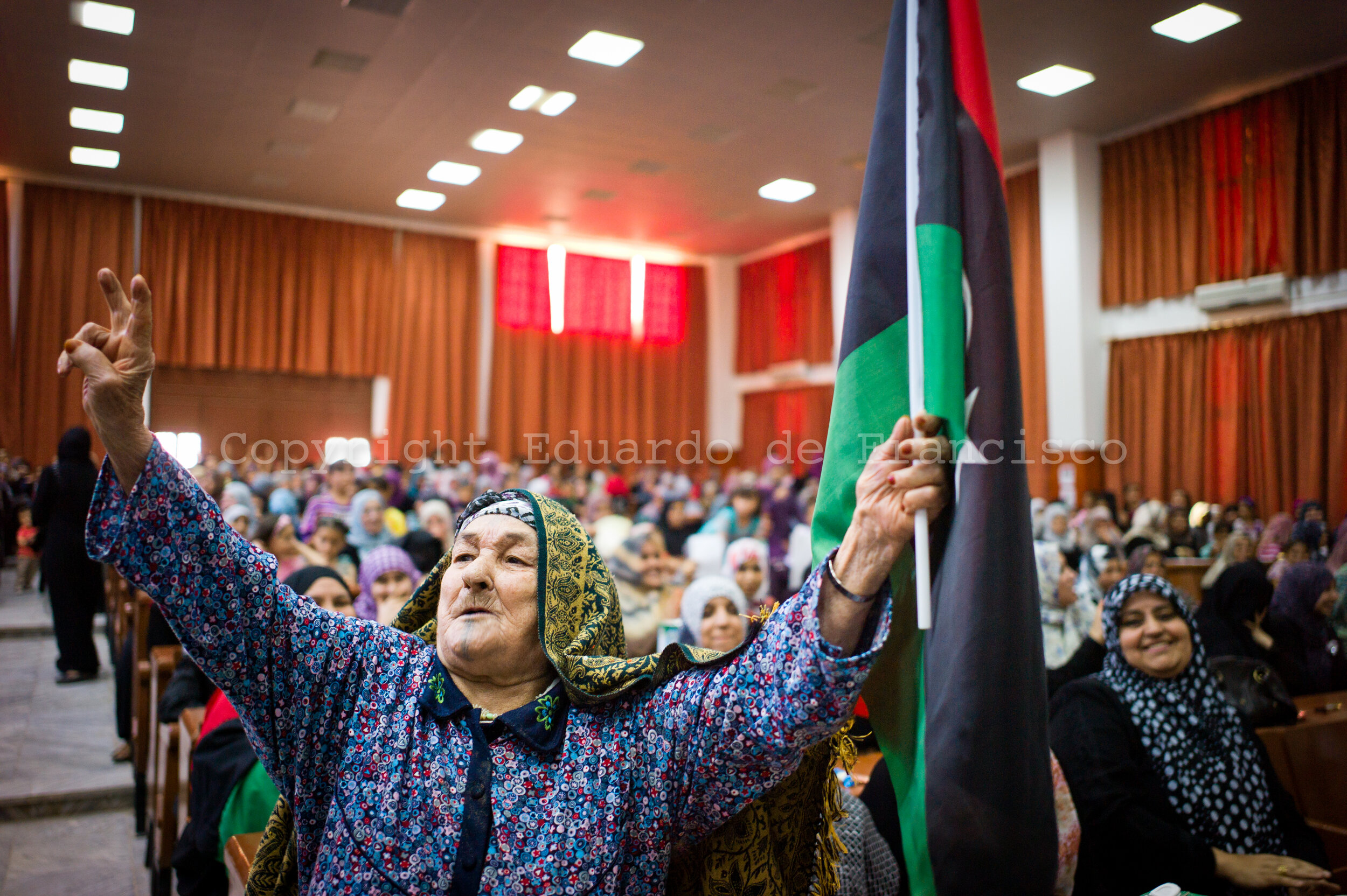  In a meeting for women organized by the charity "Alshahed" to support the war, and old woman reacts in front of the camera, raising the rebel flag and a victory sign 