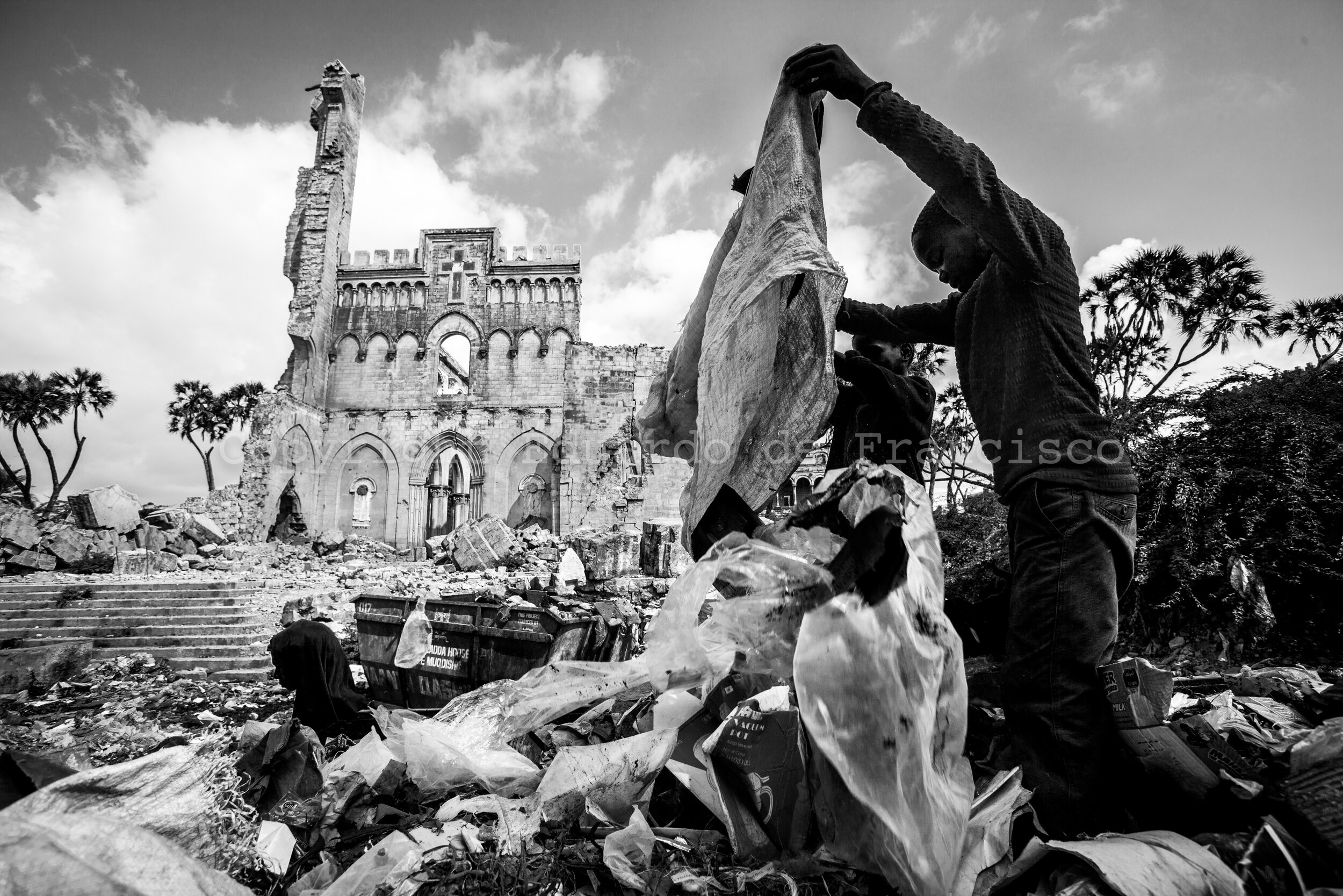  Street children foraging for anything valuable in the rubbish mounds accumulated in front of the catholic cathedral of Mogadishu. Built during the Italian colonization of the country, it was destroyed during the war, being bombed several times. Toda
