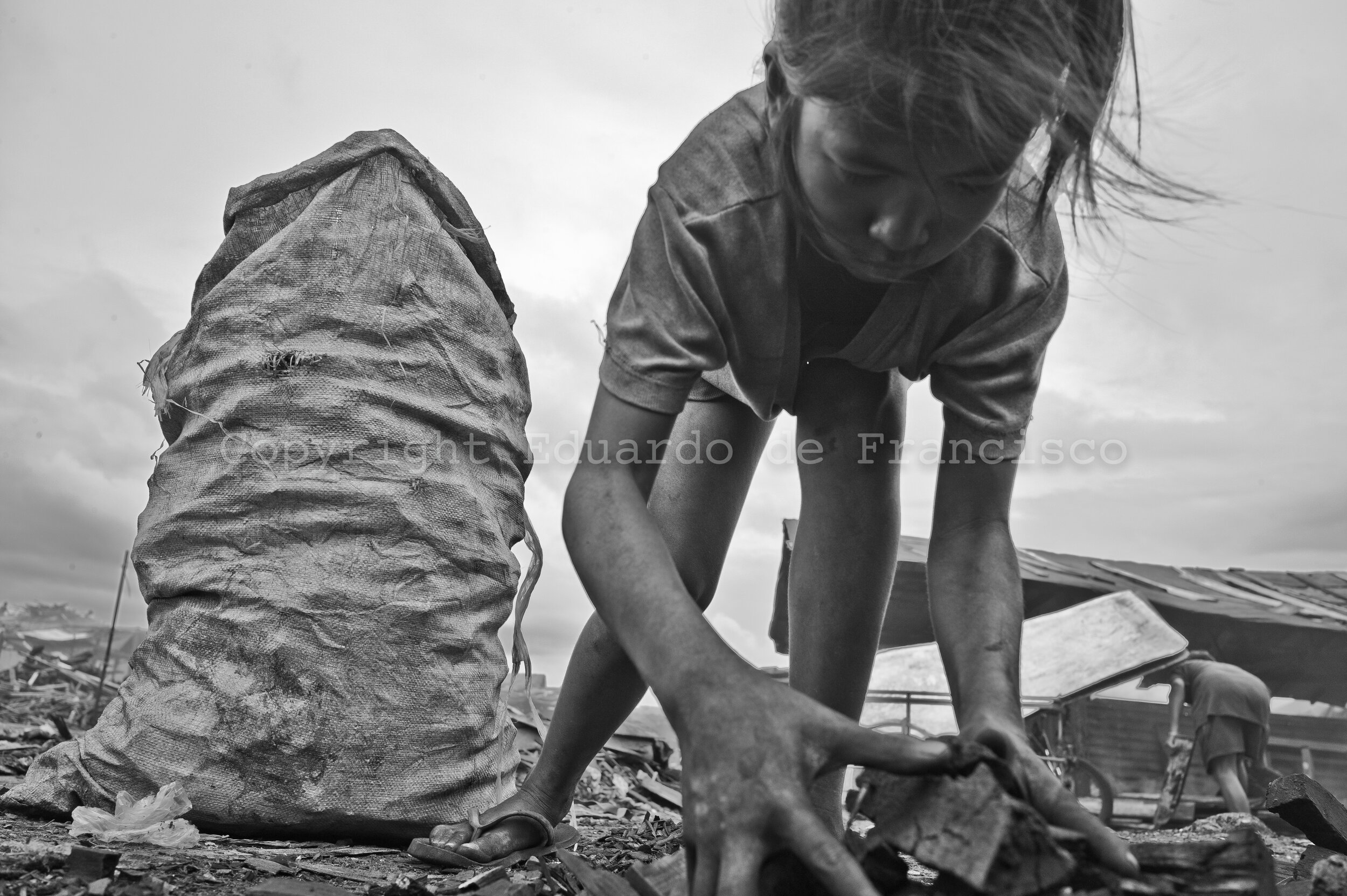  Jasmine, 12 years old. Like the rest of her siblings, she helps the family whenever extra hands are needed. Here, she packs pieces of charcoal into plastic sacks, waiting for the dealer.  In Tondo, in between 500 and 800 families depend on charcoal 