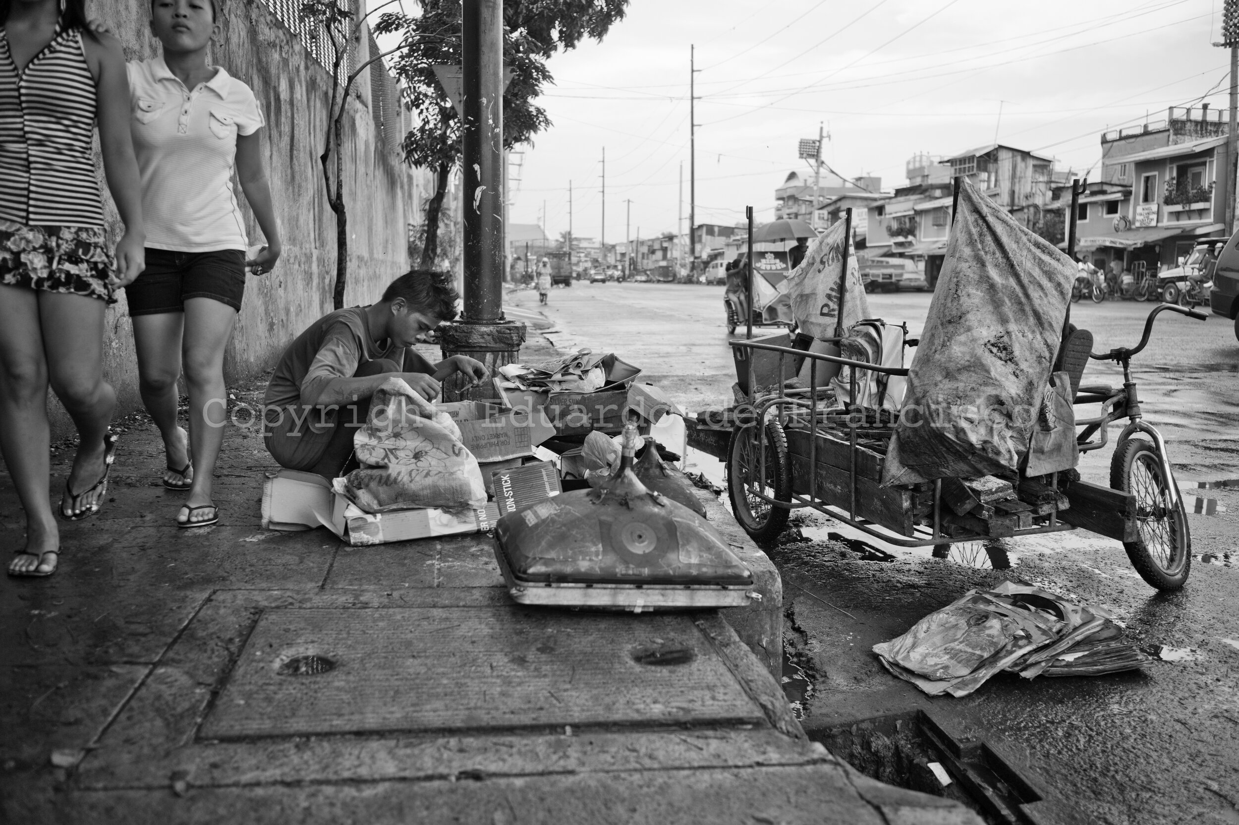  Ferdinand Marcos Avenue, early morning. A young scavenger examines what the dump trucks didn't carry, in order to grab anything that might be resold later. 
