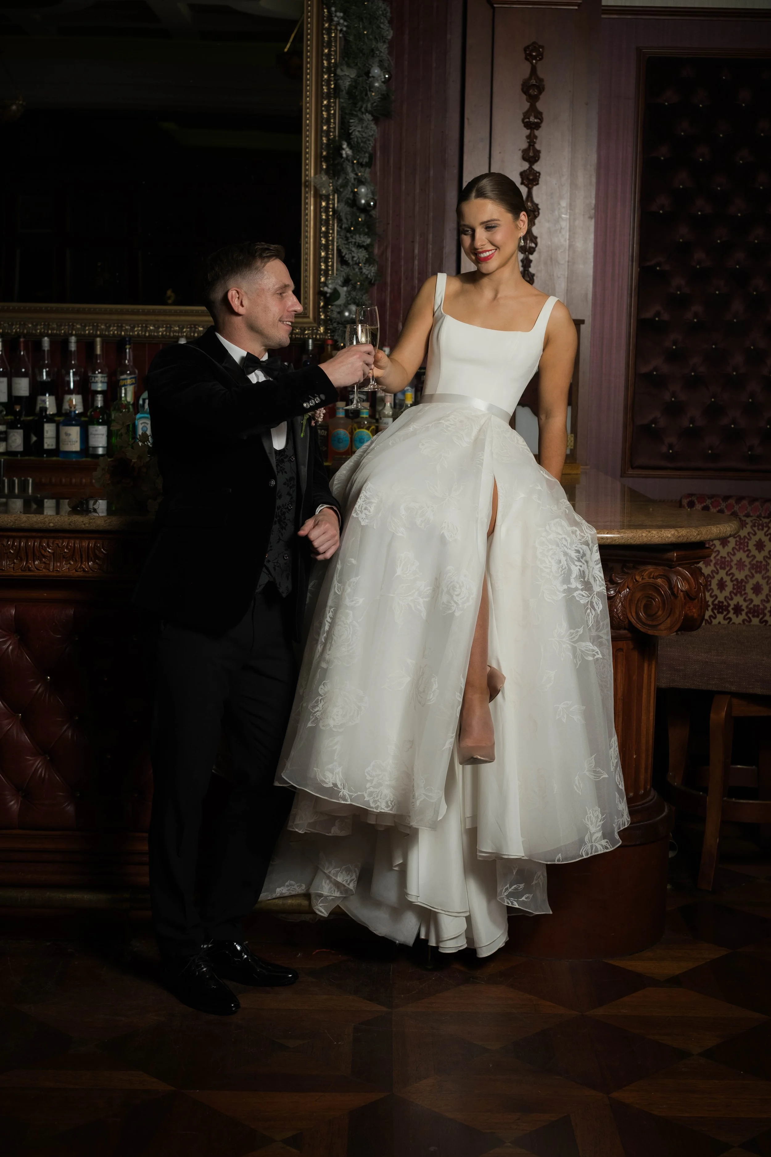bride sitting on a table with a groom holding her hand. Wedding photography!