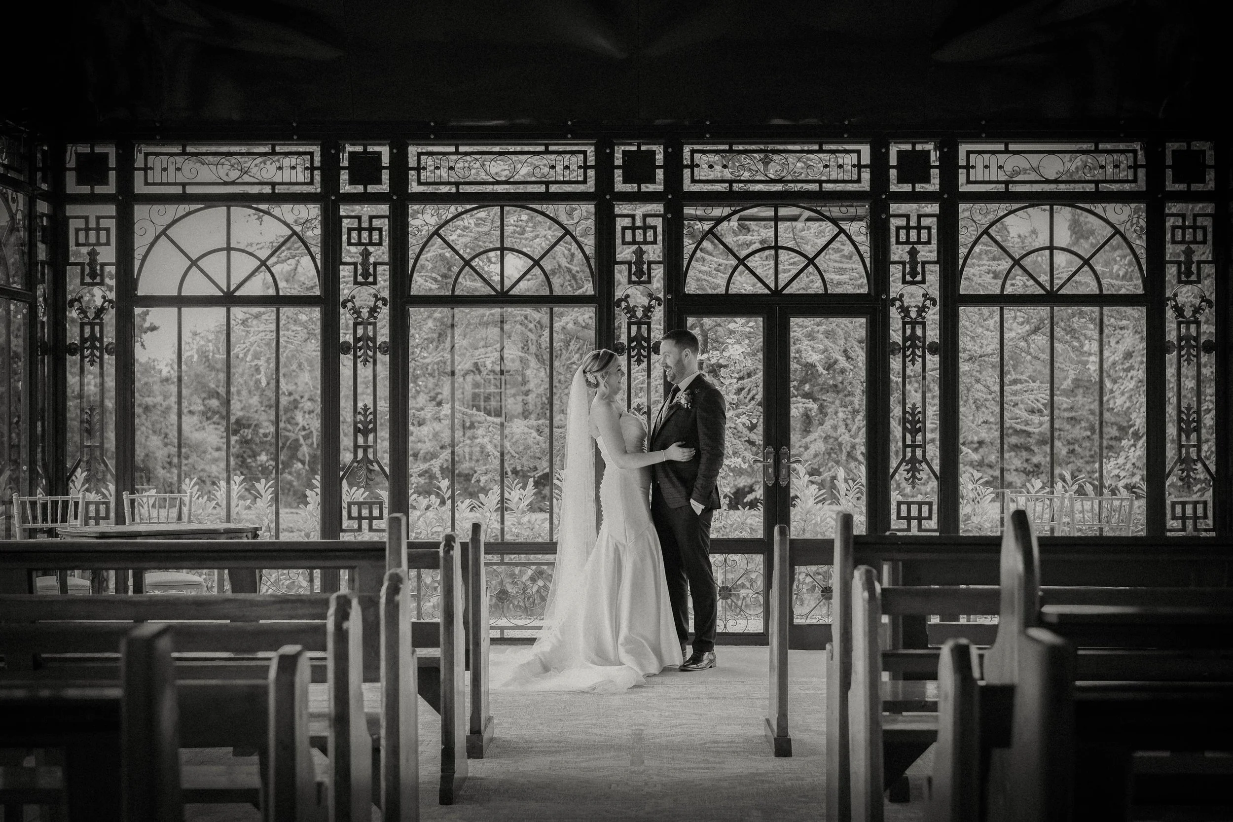 A bride and groom stand together in an ornate, empty chapel—perfect for a wedding photographer to capture the moment.