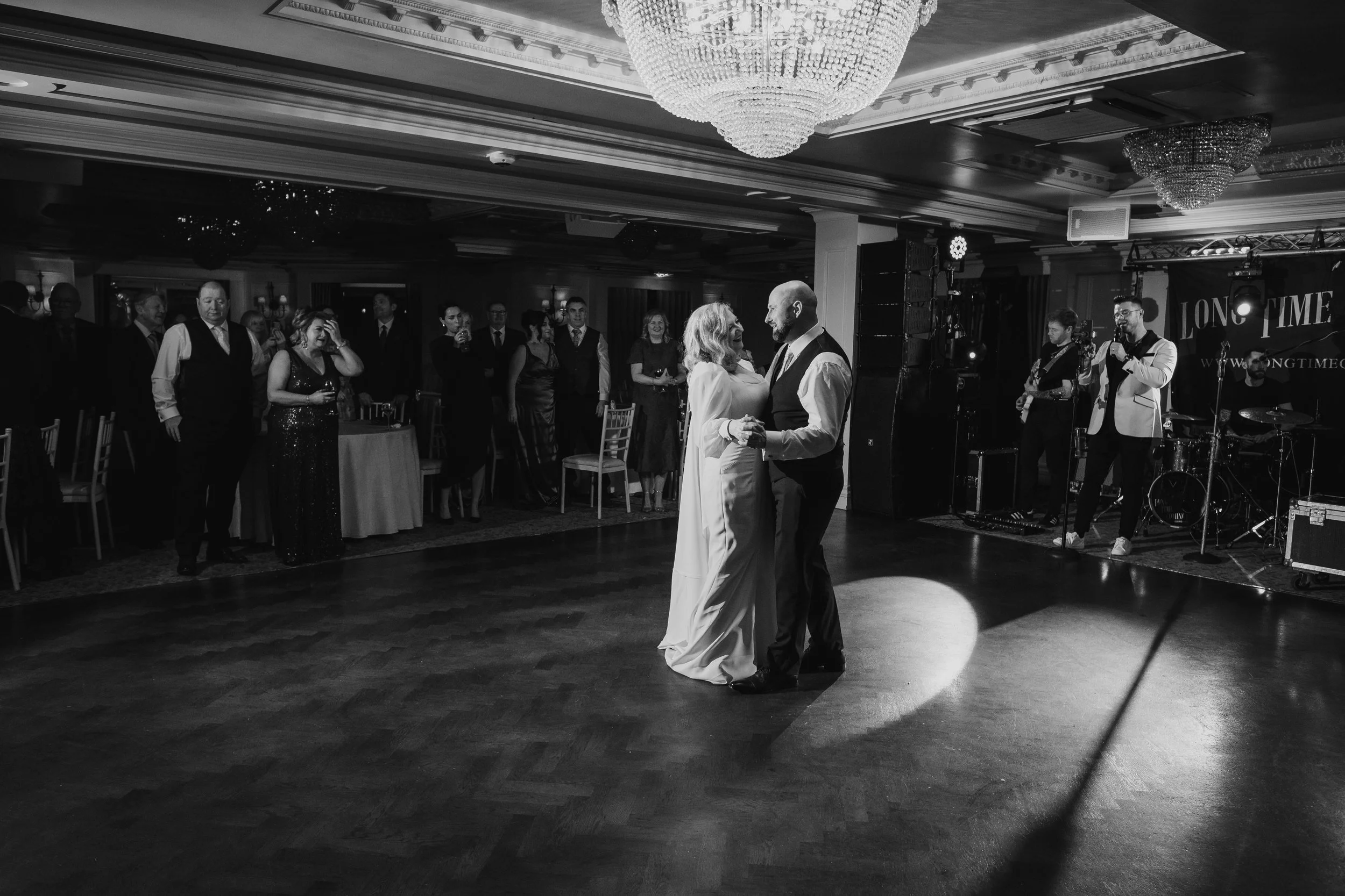 Bride and groom's first dance with a band in the background in a beautiful hotel ballroom. Captured in black and white.