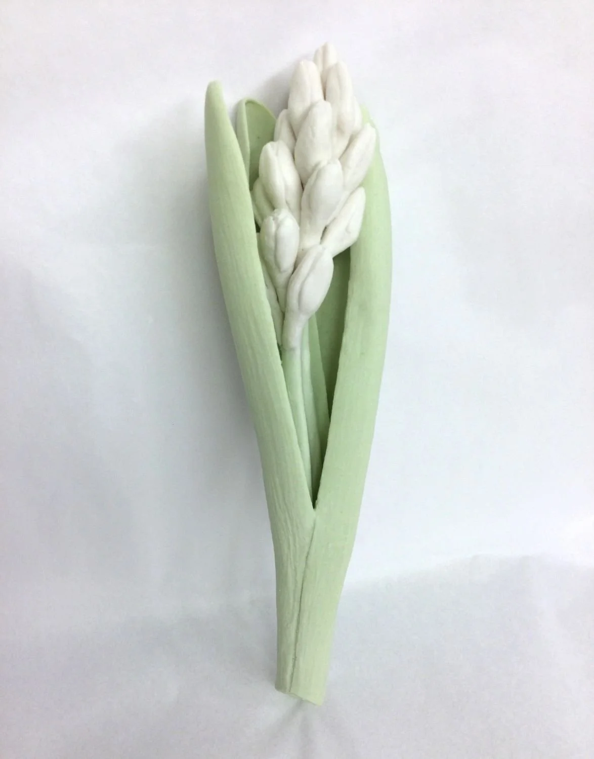 White Hyacinth Budding III (cat#22.6), 2022, cone 6 hand modelled tinted porcelain, wall mounted, 9 x 2.5 inches (23 x 6.5 cm), $800 Cdn.