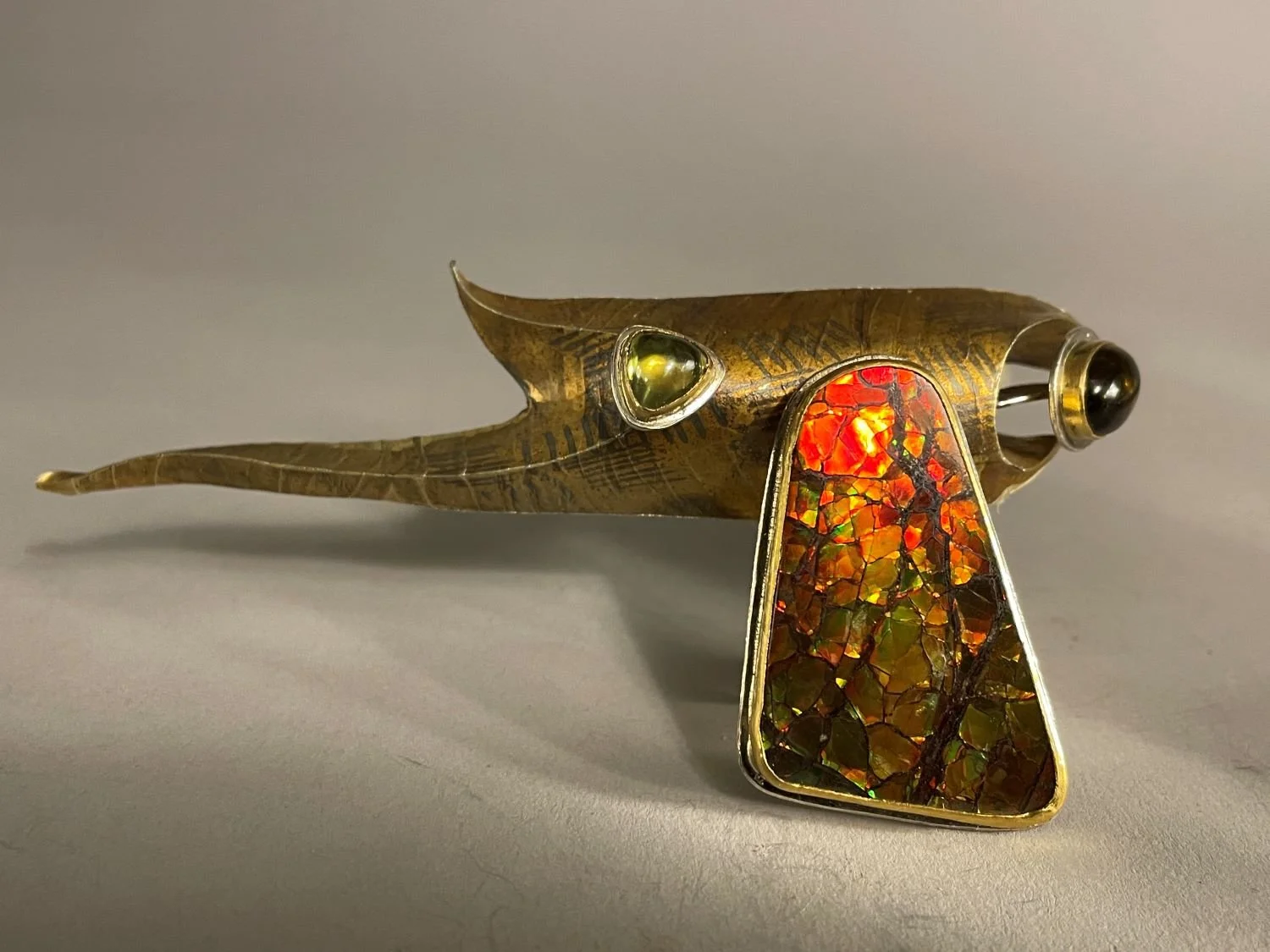 ‘Bearpaw Red’ Brooch (Swoop Series), 1997, materials 18k gold laminate, Sterling, 24k Bezels, Zircon Oval, Large Ammolite
Trapezoid, Trillion Peridot, (10.4x5.3x2.5 cm), $3400 Cdn.
